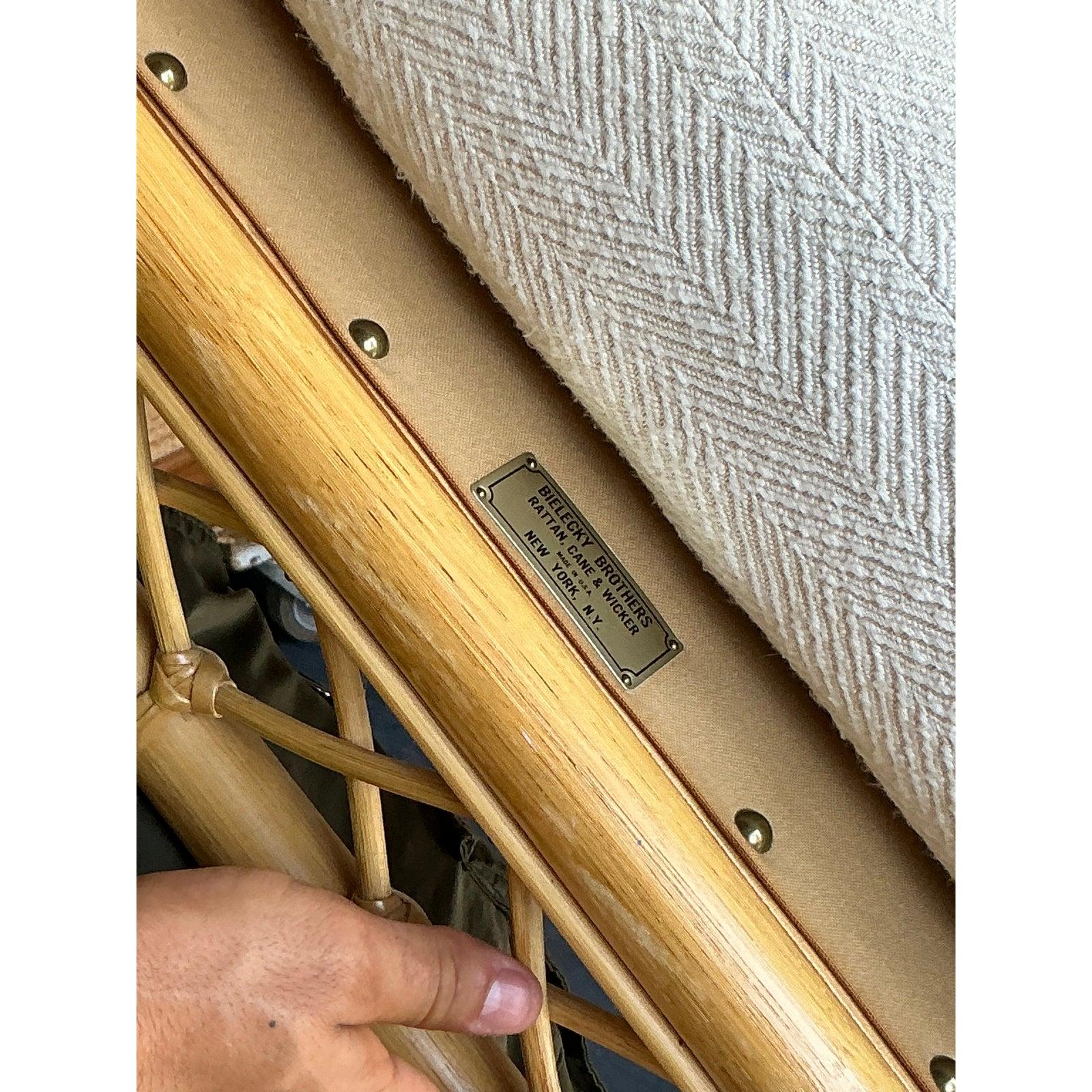 Discover the unparalleled craftsmanship of this vintage rattan bench by the legendary American maker, Bielecky Brothers. This piece is a testament to luxury rattan design, featuring beautifully reeded top and bottom rails that frame intricate