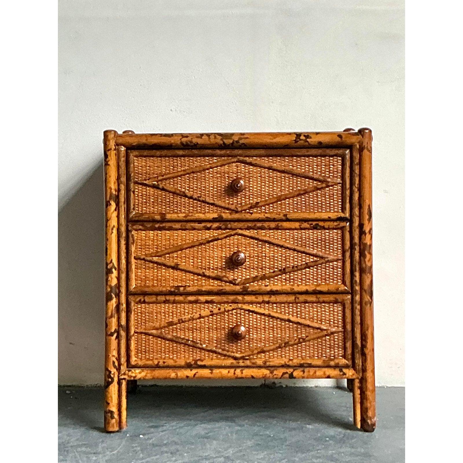Infondi nel tuo spazio il calore organico e la raffinatezza tropicale di questa squisita cassettiera vintage in rattan tartarugato. Il pezzo presenta una robusta struttura in bambù 
