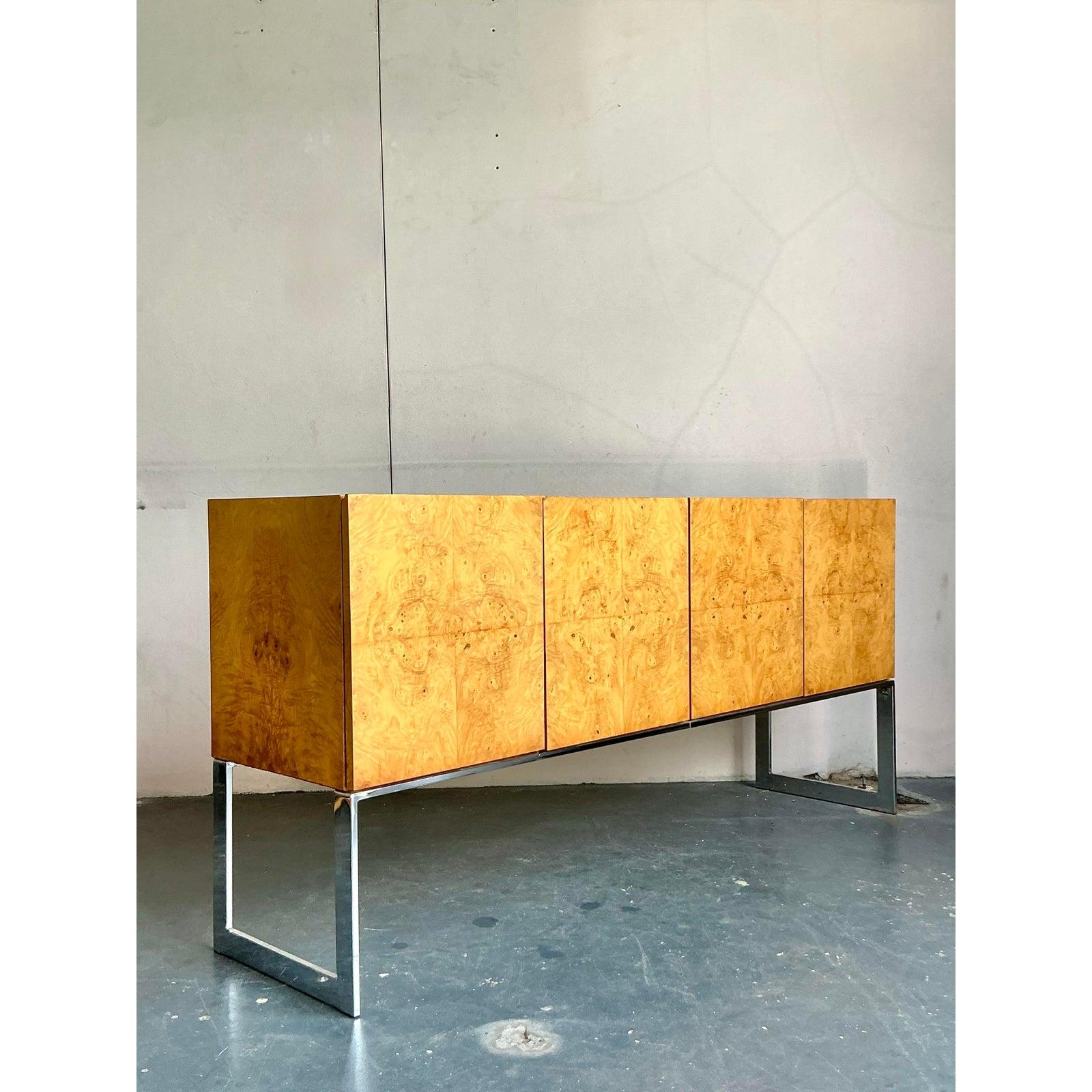 Embodying the sophisticated spirit of American Modernism, this stunning credenza channels the iconic designs of Milo Baughman for Thayer Coggin. Its defining feature is the spectacular bookmatched olive ash burl veneer, creating a captivating,