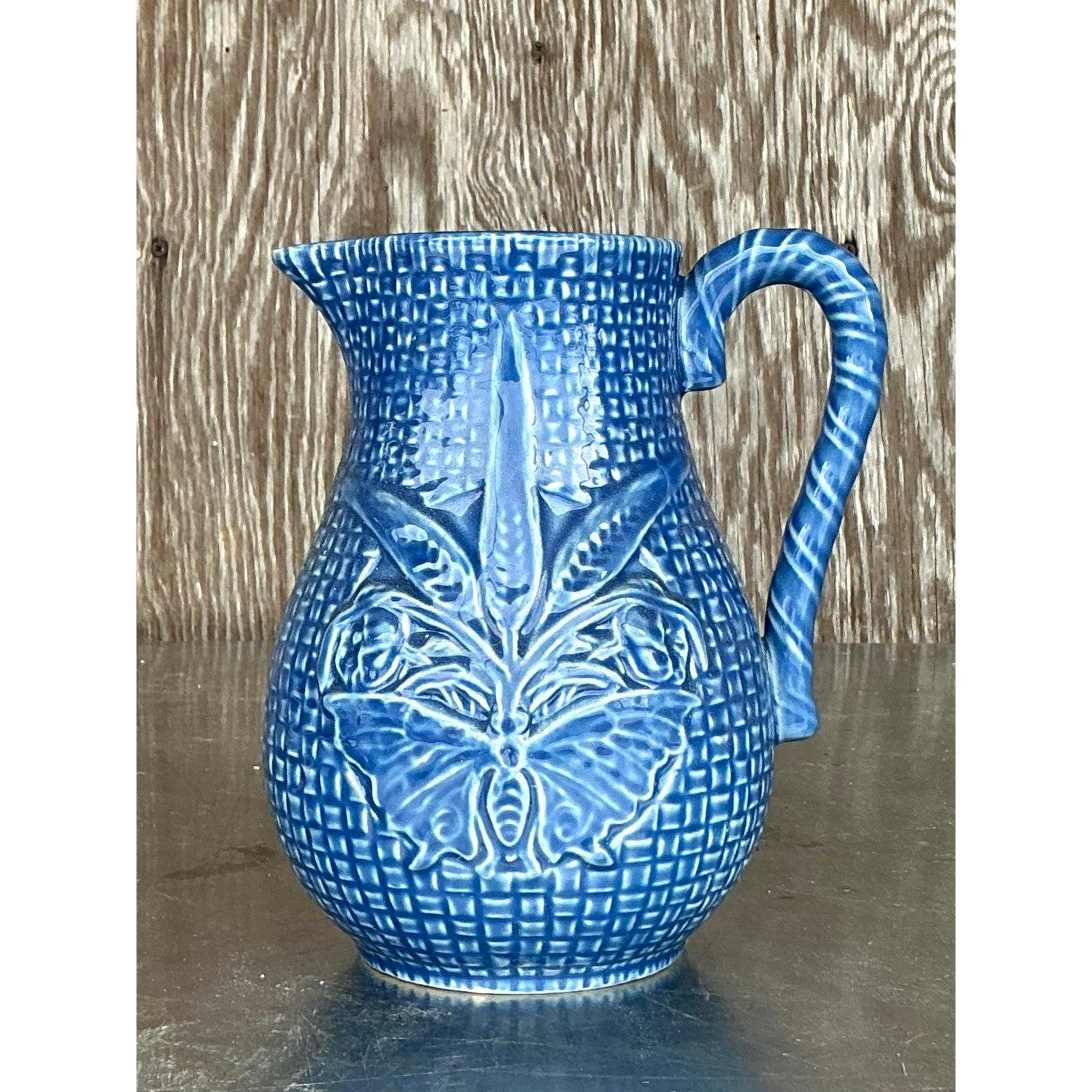 Añade un atrevido estallido de color y encanto del viejo mundo a tu mesa o estantería con esta impresionante jarra de cerámica azul vintage de Bordallo Pinheiro. Hecha a mano en Portugal, esta pieza de intrincados detalles presenta un esmalte de