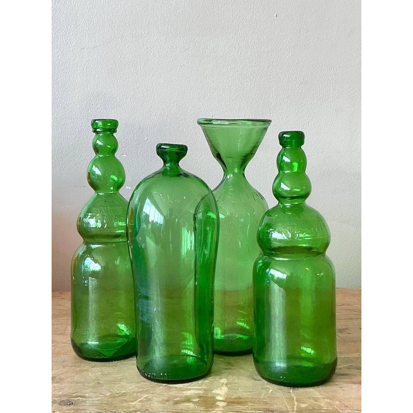 Elevate your interior with this enchanting collection of four vintage Boho green glass bottles, each offering a unique silhouette and undeniable charm. This curated set embodies a relaxed yet sophisticated aesthetic, perfect for adding a touch of