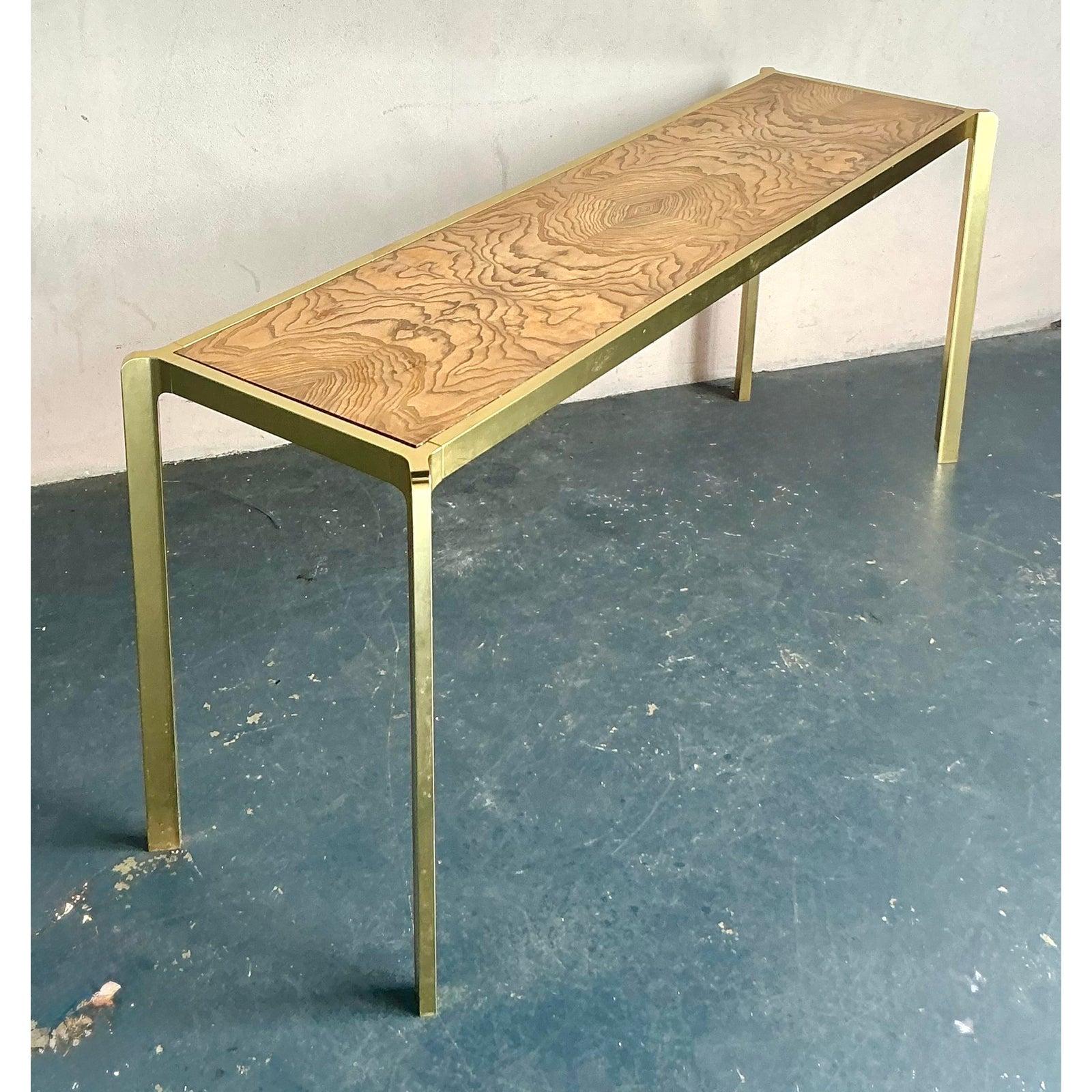 This exquisite vintage console table is a testament to the enduring appeal of Boho-chic design, seamlessly blending natural elements with sophisticated metallic accents. Crafted with a stunning burl wood top, its distinctive grain patterns create a