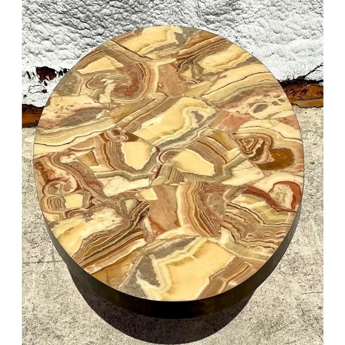 Cette table basse exceptionnelle témoigne de l'utilisation de matériaux luxueux et de formes sculpturales privilégiées dans le design italien du milieu du siècle et postmoderne. Le plateau présente une mosaïque ovale très décorative d'onyx taillé en