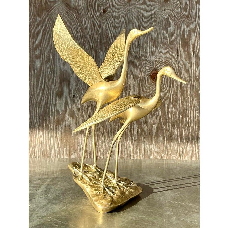Introduci un'eleganza senza tempo nel tuo arredamento con questa splendida coppia di gru in ottone vintage. Splendidamente realizzate con linee aggraziate e dettagli intricati, queste gru si ergono in bilico su una base in ottone testurizzato che