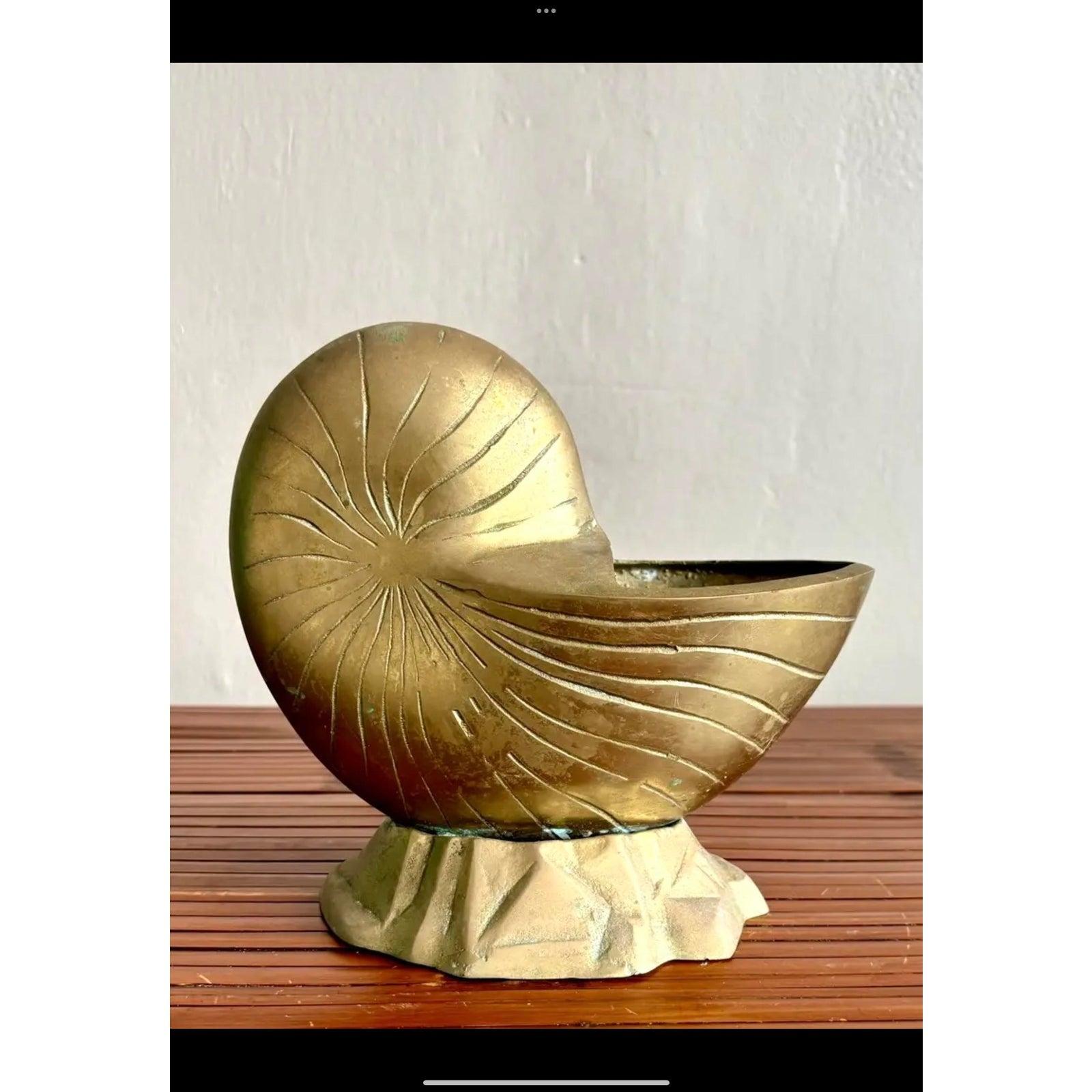 Chauffe-cuillère en laiton avec coquille de nautile, détails en spirale gravés et base texturée. Sa silhouette audacieuse et ses lignes sculpturales lui confèrent une forte présence dans n'importe quel décor. Parfait pour mettre en valeur des