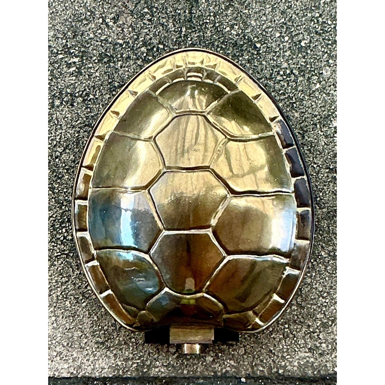 Illuminate your space with the captivating allure of this vintage brass tortoise shell sconce. Its unique, sculptural form, crafted from lustrous brass, brings a touch of whimsical sophistication and warm metallic glow to any interior. The