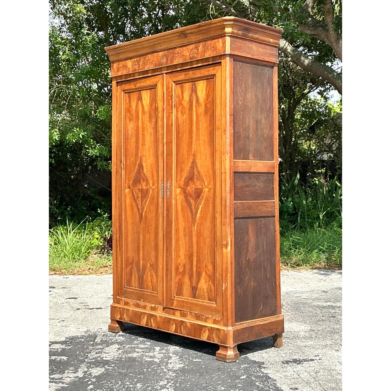 Uncover a piece of timeless grandeur with this magnificent Vintage Burl Wood Armoire, a striking fusion of sophisticated design and natural artistry. This grand cabinet showcases exquisite burl wood veneers across its two expansive doors, creating