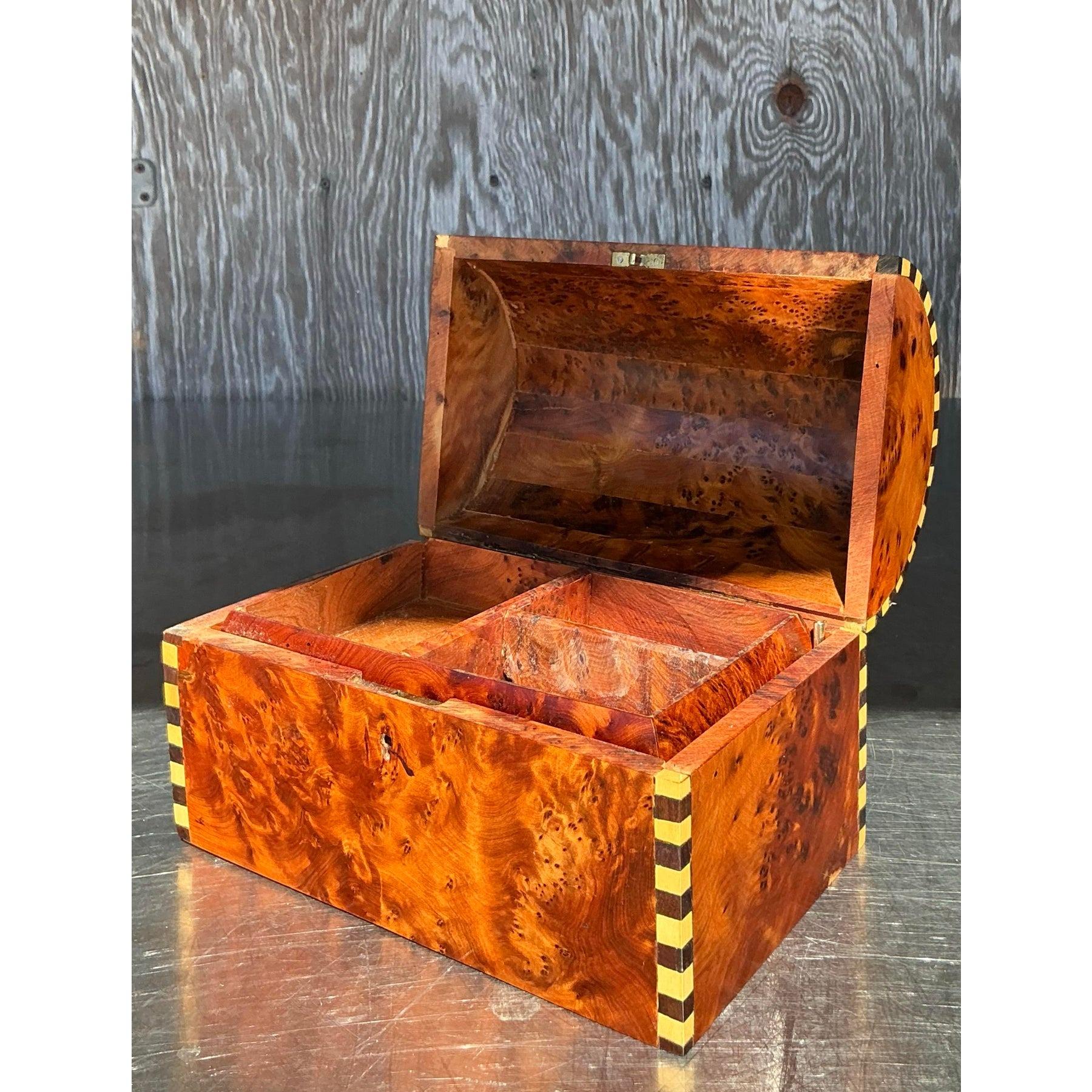 Eleva tus soluciones de almacenamiento con este exquisito cofre del tesoro de madera burl vintage. Con un asombroso veteado de madera burlada natural de tonos ricos y cálidos y patrones intrincados, esta pieza se acentúa con un delicado diseño de