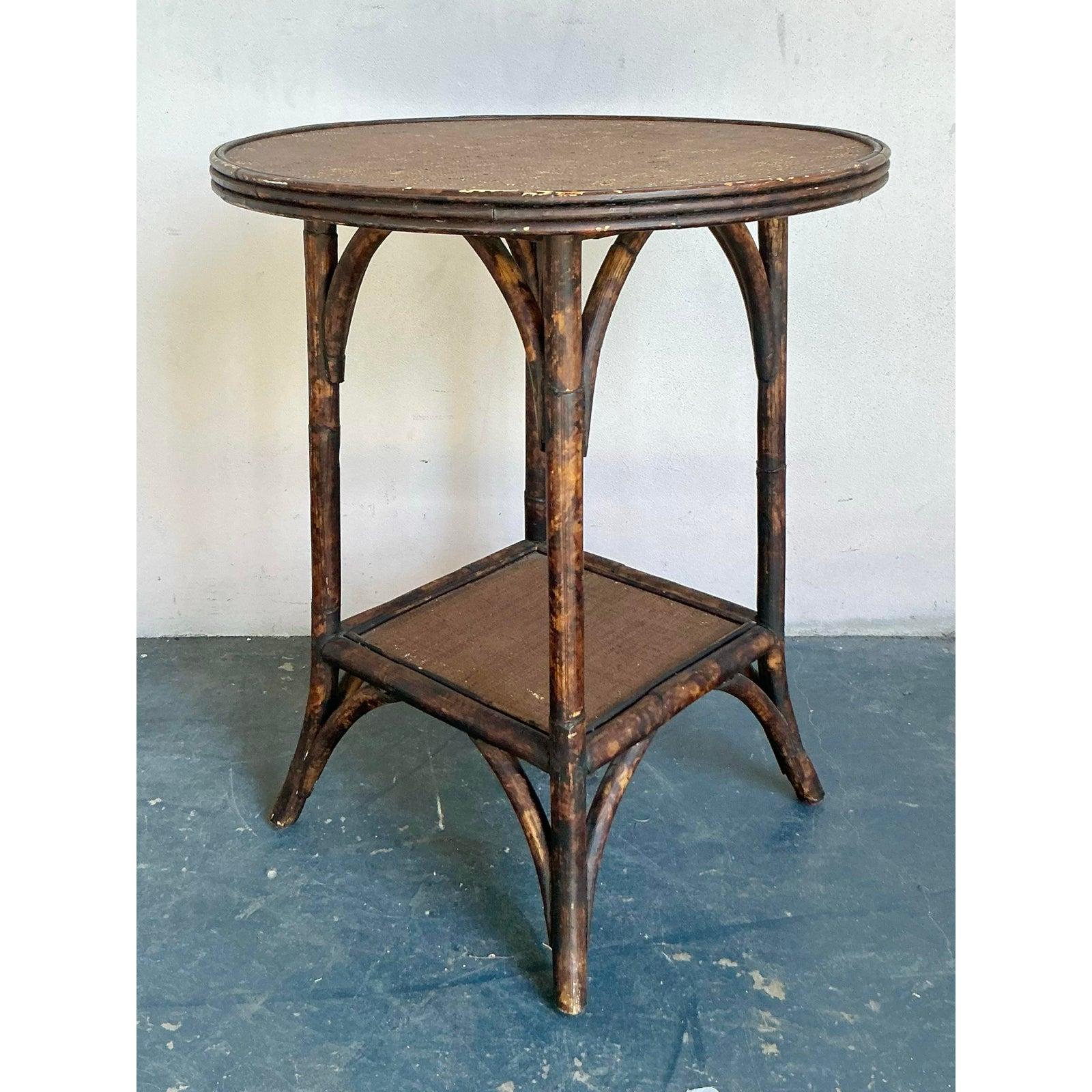 Introduce a touch of exotic charm and natural texture to your living space with this captivating vintage Boho Chic side table, crafted from burnt bamboo and rattan. This enchanting piece features a beautifully darkened bamboo frame that exudes a
