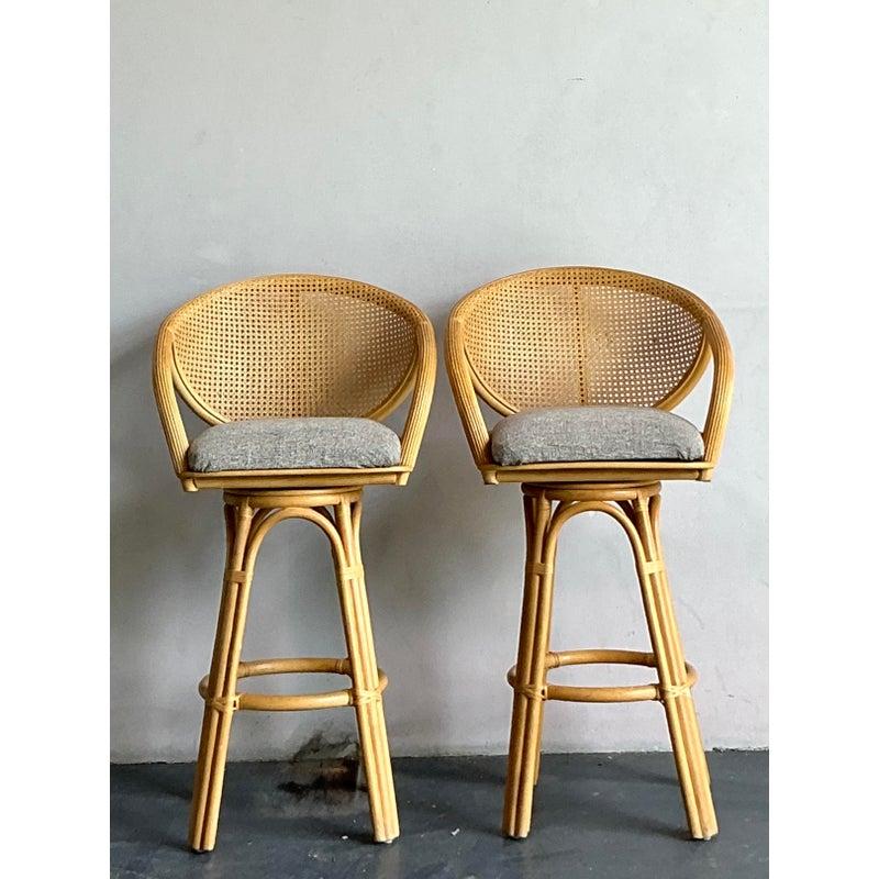 Infuse your home bar or kitchen island with organic charm and sophisticated comfort with this delightful pair of vintage Boho Chic bar stools. Each stool is beautifully crafted from bent rattan, forming an elegant, enveloping frame that supports a