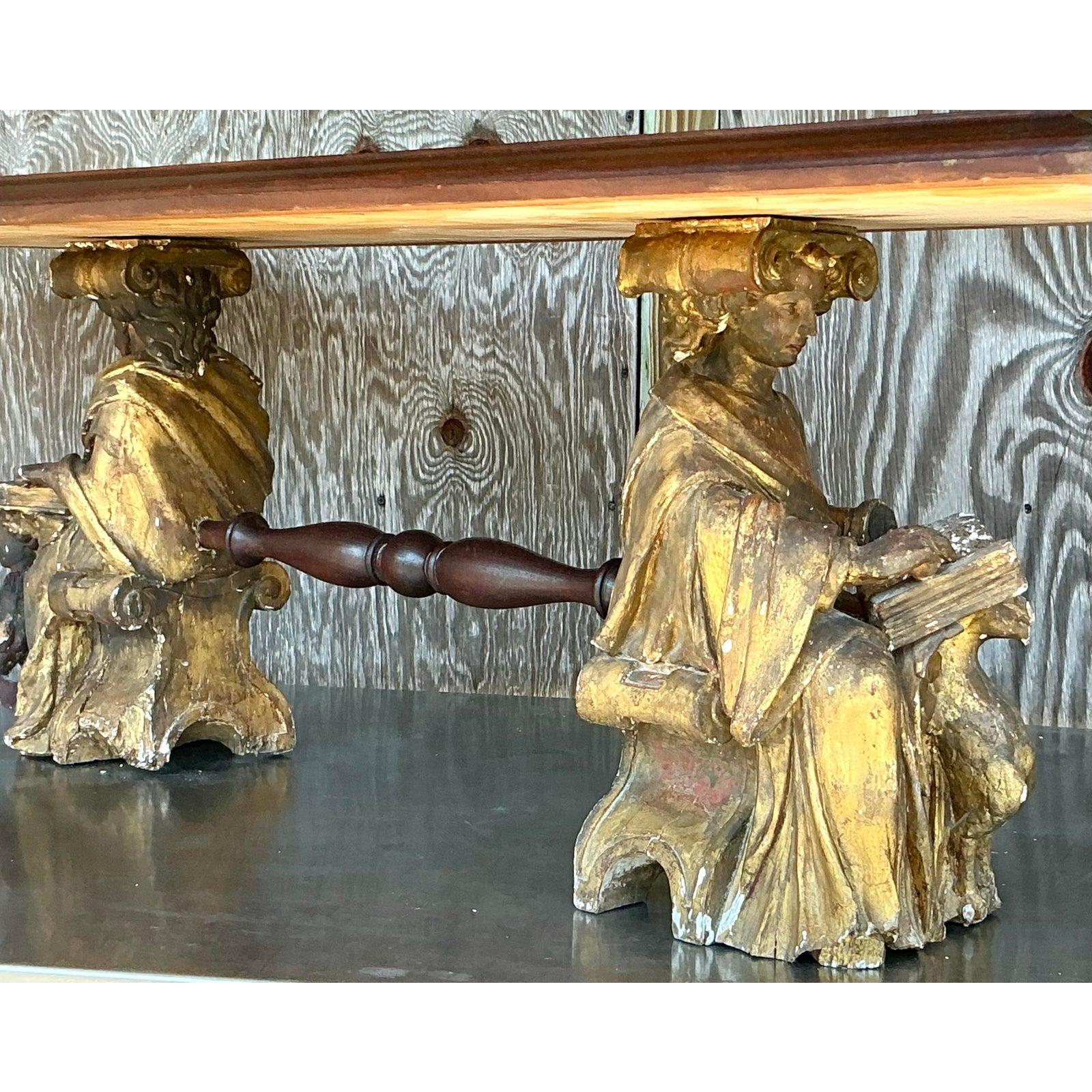 This breathtaking vintage carved angel coffee table is a one-of-a-kind statement piece, blending rustic charm with intricate craftsmanship. The hand-carved wooden base features two seated angelic figures, exuding an ethereal presence that adds depth