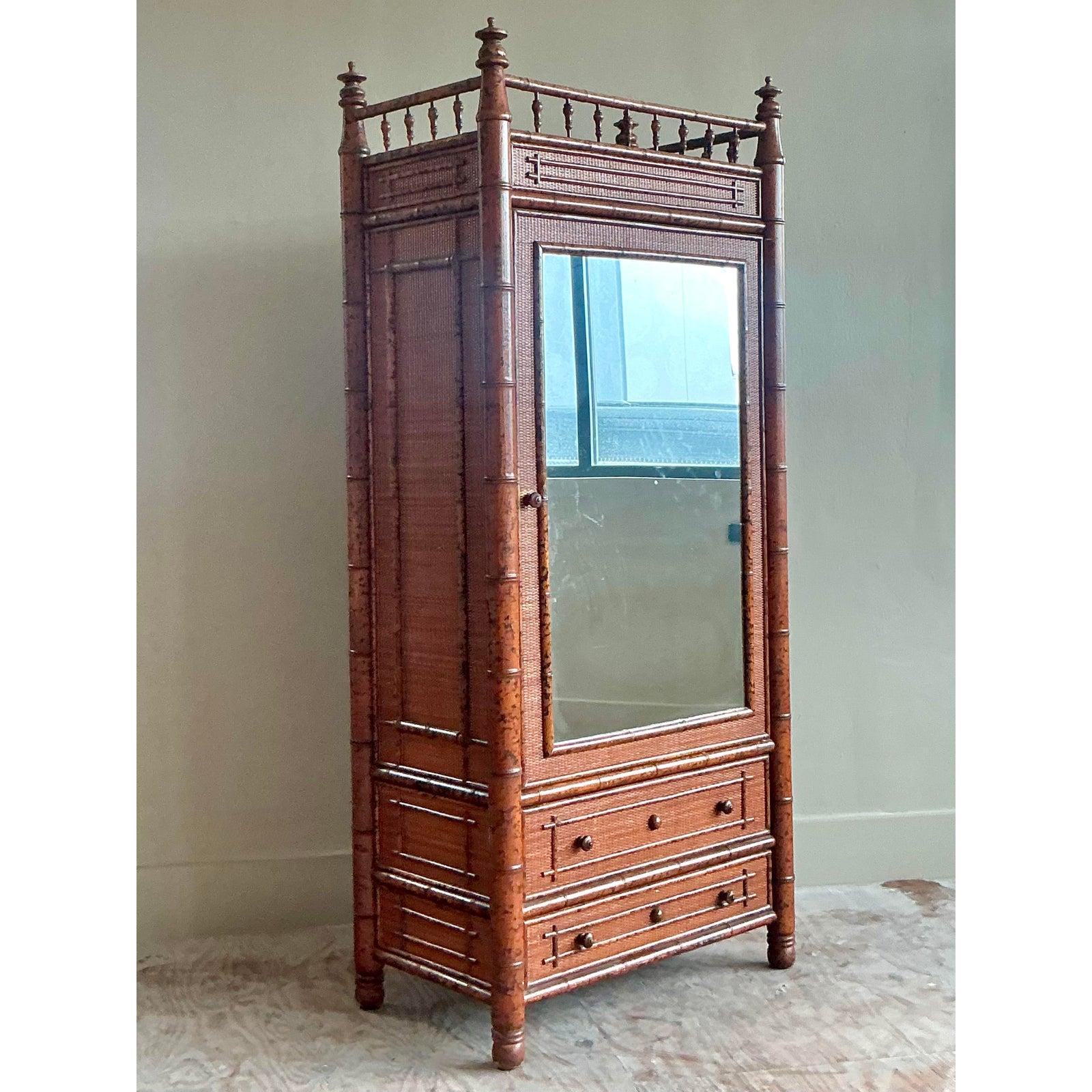 Questo armadio d'epoca è un pezzo da novanta, che trasmette magistralmente il fascino esotico degli stili British Colonial e Chinoiserie. L'intera struttura è realizzata in legno tornito e rifinito in modo da assomigliare a un bambù con una ricca