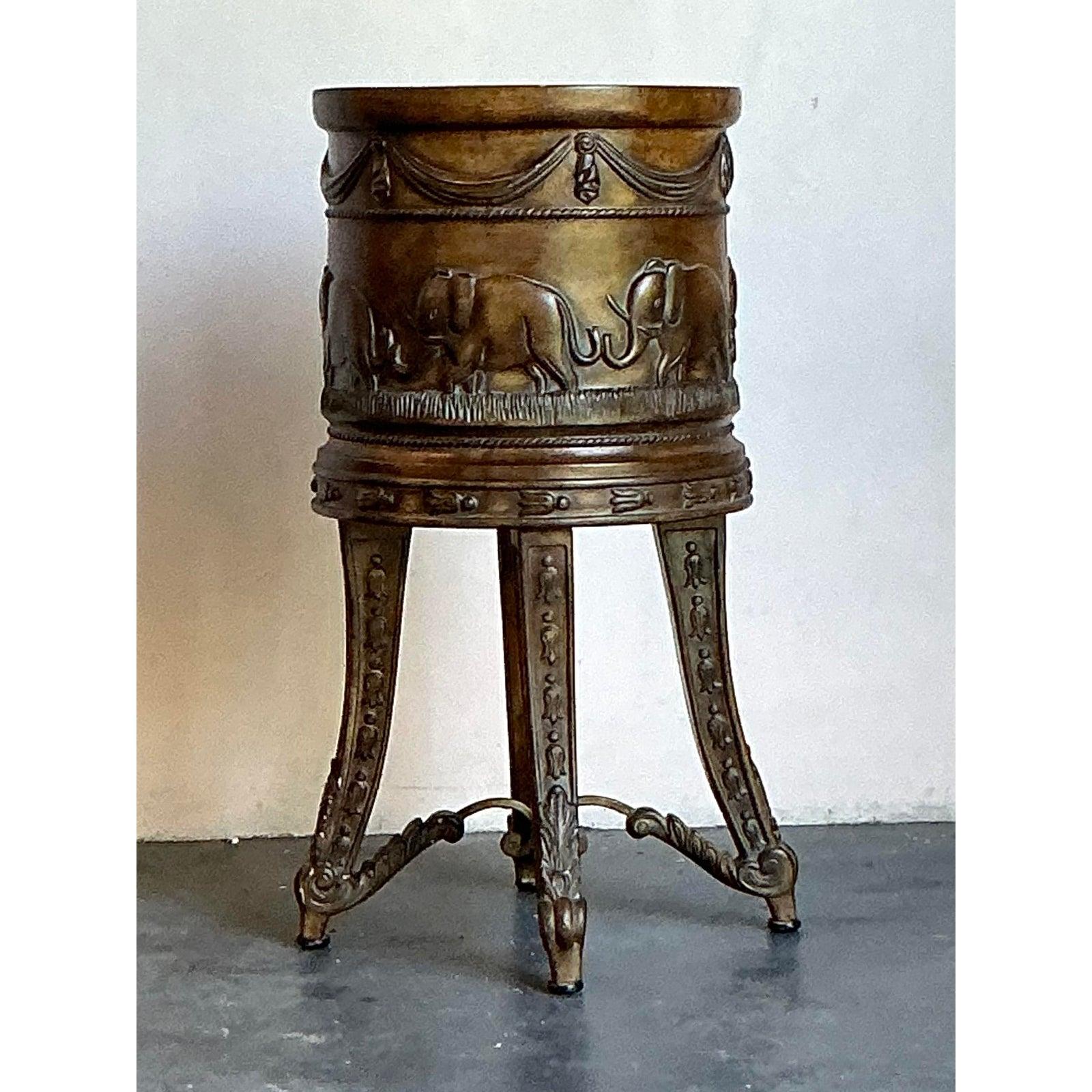 Infusez une touche de sophistication mondiale dans votre intérieur avec cette étonnante jardinière en laiton vintage et son support. Cette pièce exceptionnelle présente une magnifique frise gaufrée d'éléphants en marche, un motif classique qui