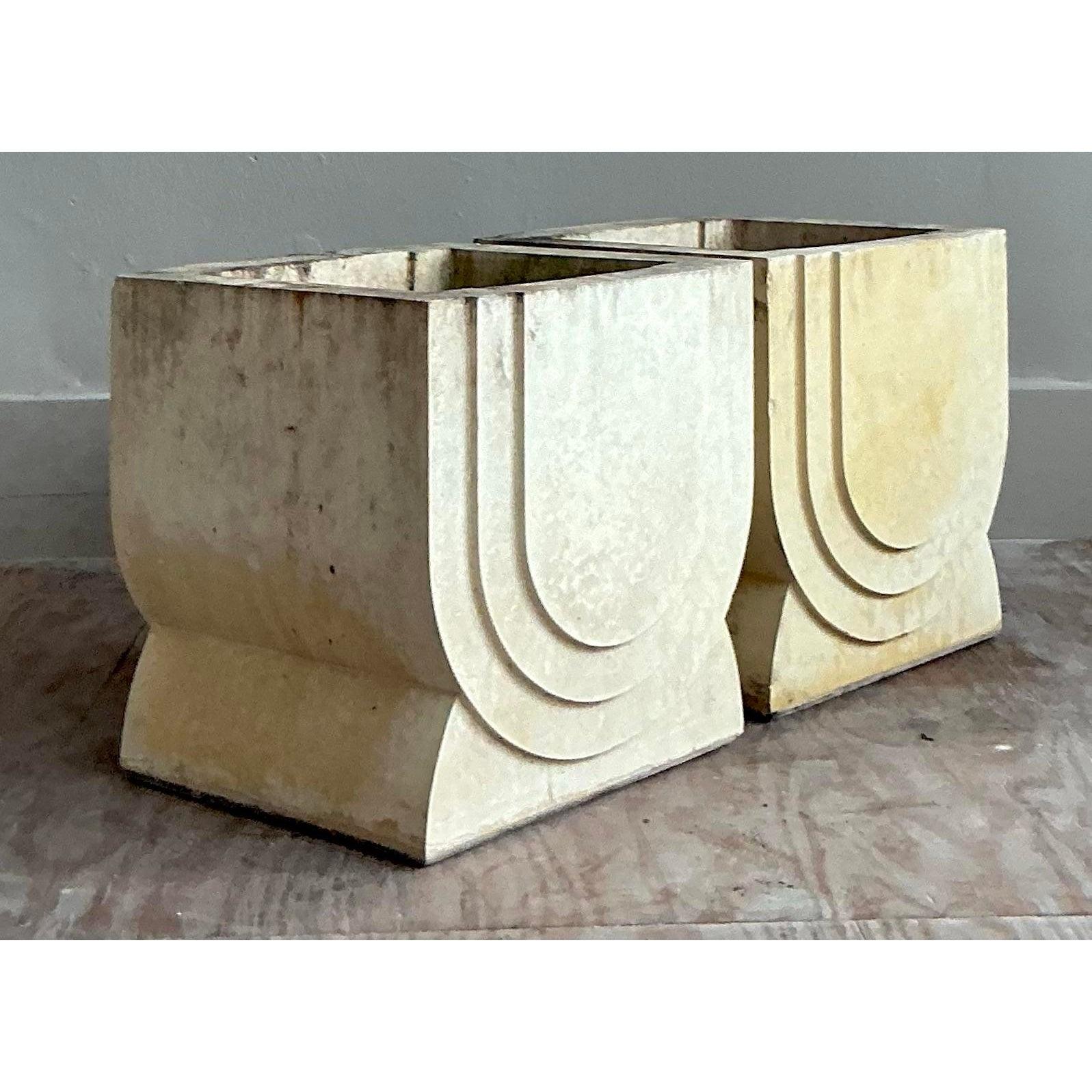 Exuding a timeless sense of architectural grandeur, this impressive pair of vintage planters is expertly crafted from heavy, substantial carved stone. The design features bold, geometric stepped details highly reminiscent of the Art Deco era,