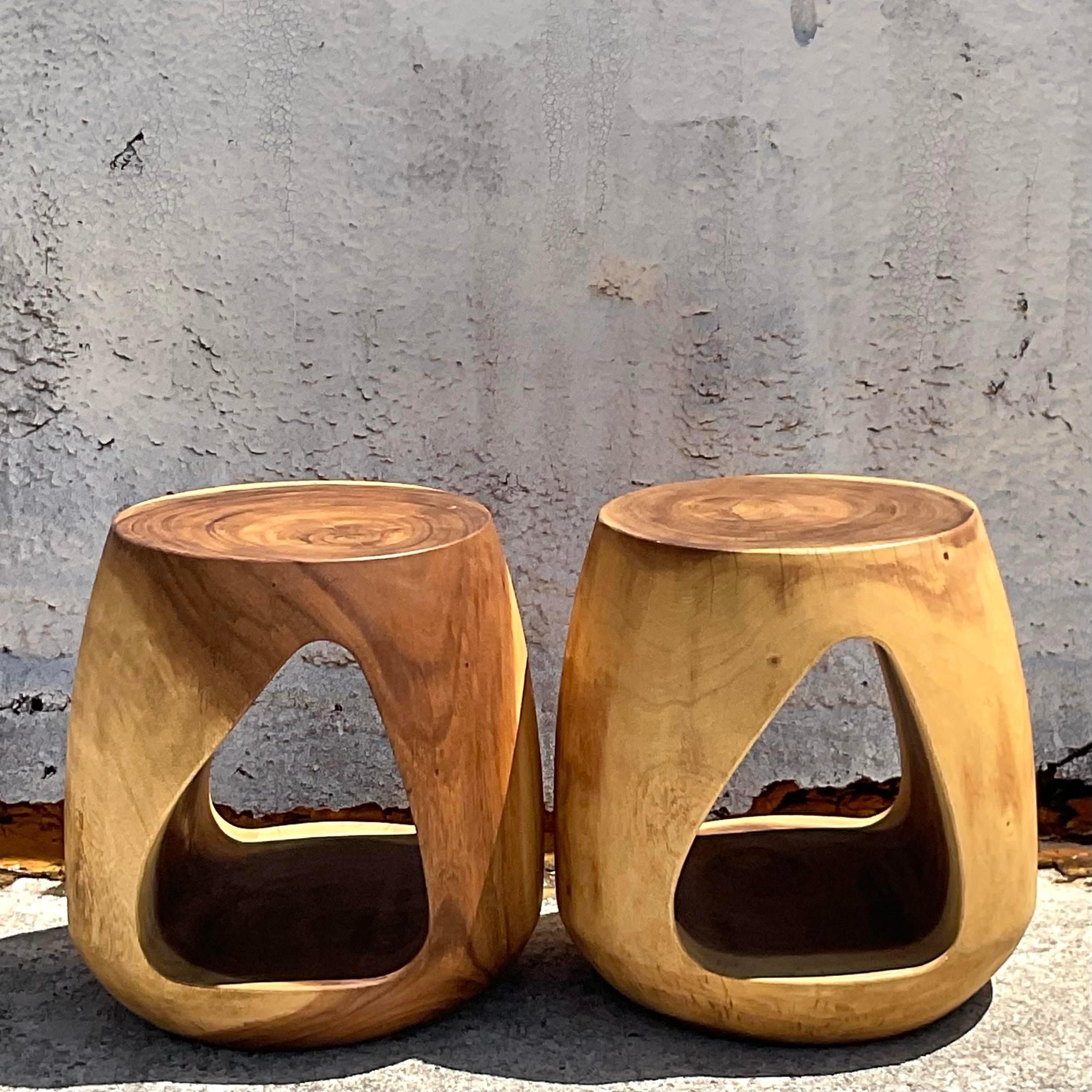 Elevate your living space with this Pair of Vintage Boho Carved Stump Low Stools, embodying the essence of American craftsmanship and style. Each stool features intricate carvings that evoke a sense of rustic charm and natural beauty, perfect for