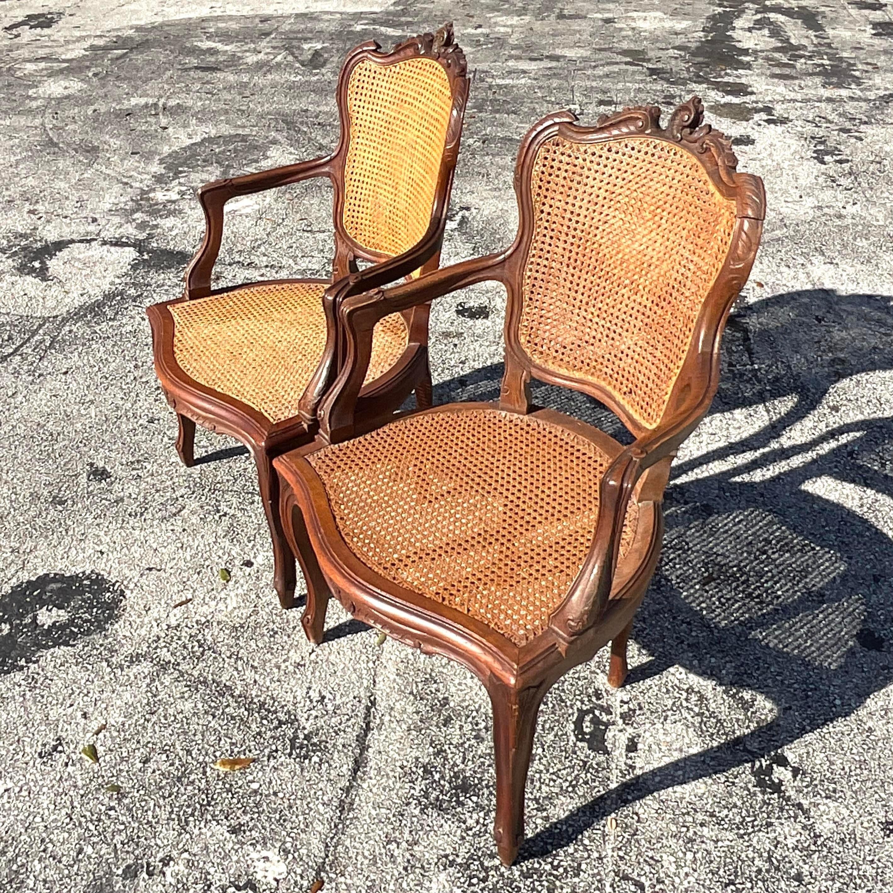 A fabulous pair of vintage Boho arm chairs. Beautiful hand carved detail with chic inset cane panels. Acquired from a Palm Beach estate.