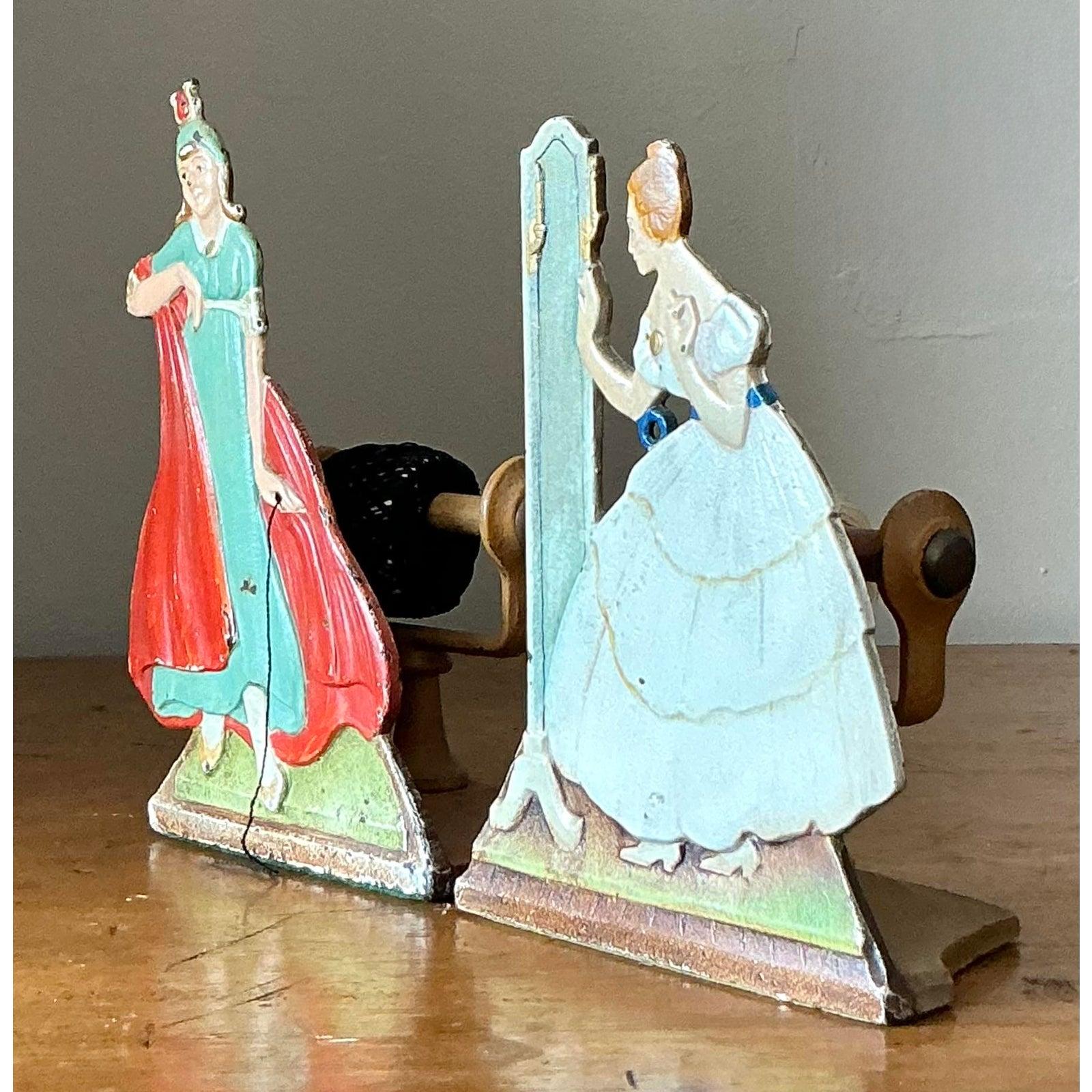 Aggiungi un tocco di fascino nostalgico e di carattere al tuo spazio con questa deliziosa coppia di statuette di donna in ghisa vintage. Realizzata in ghisa pesante con una splendida finitura dipinta a mano, ogni figura evoca la grazia dell'epoca