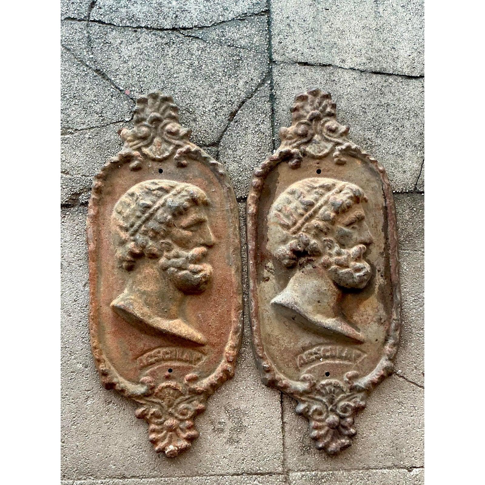 Evoca la grandezza dell'antichità classica con questa coppia di targhe da parete in ghisa vintage. Ogni targa presenta il nobile profilo di Asclepio (Esculapio), il dio greco-romano della medicina e della guarigione, reso in un potente bassorilievo.