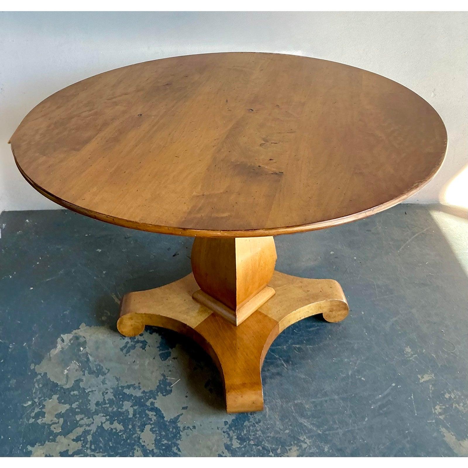 Cette table centrale remarquable rend hommage aux courbes élégantes et aux formes solides du style Biedermeier du début du XIXe siècle, interprétées avec un flair moderne et substantiel. Cette table se distingue par sa base monumentale à piédestal