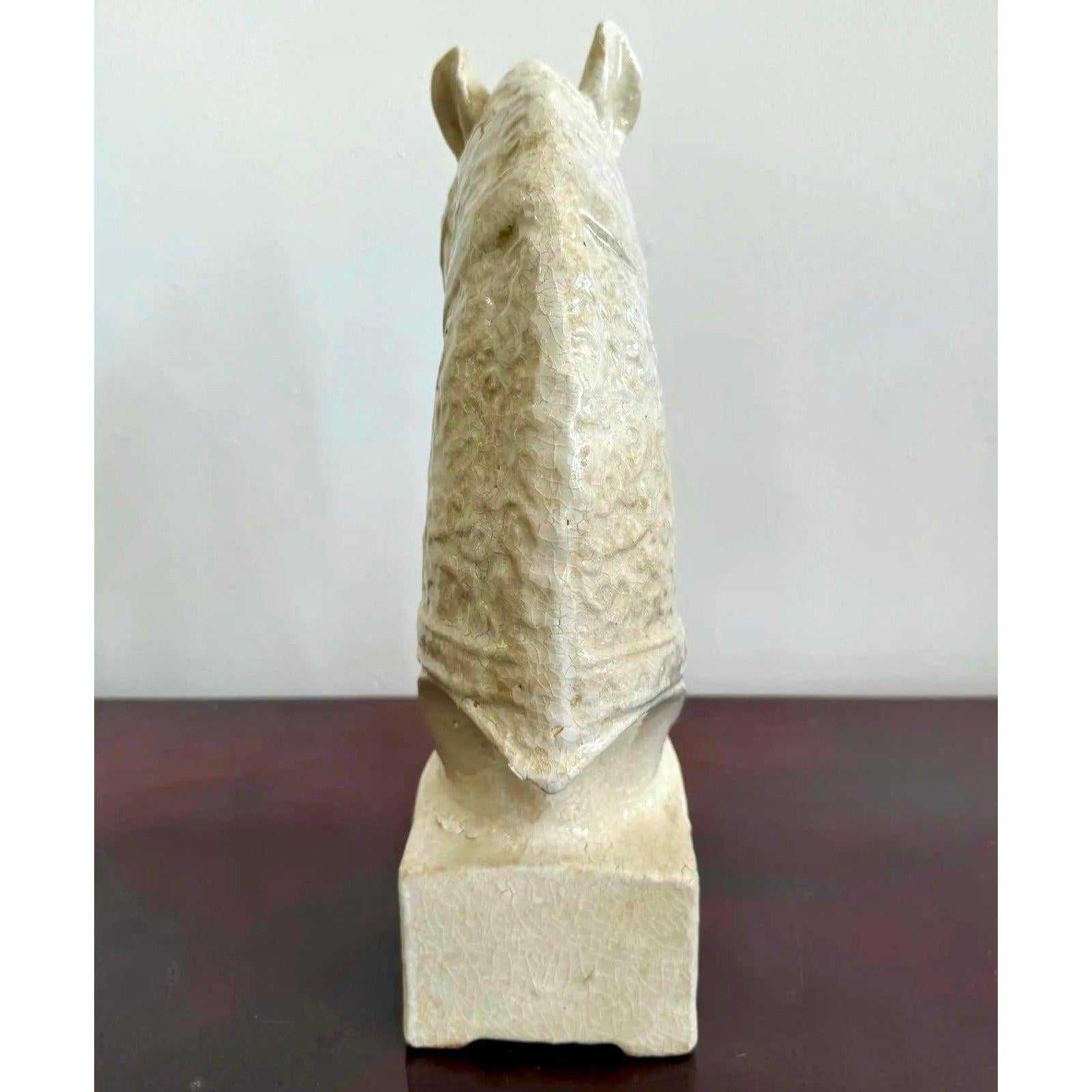 Questo busto di cavallo in ceramica bianca cattura un momento di tranquilla grazia, con il mento del cavallo delicatamente chinato sul petto in un gesto di umiltà o di riposo. Sottili impronte decorate adornano la superficie, aggiungendo una texture