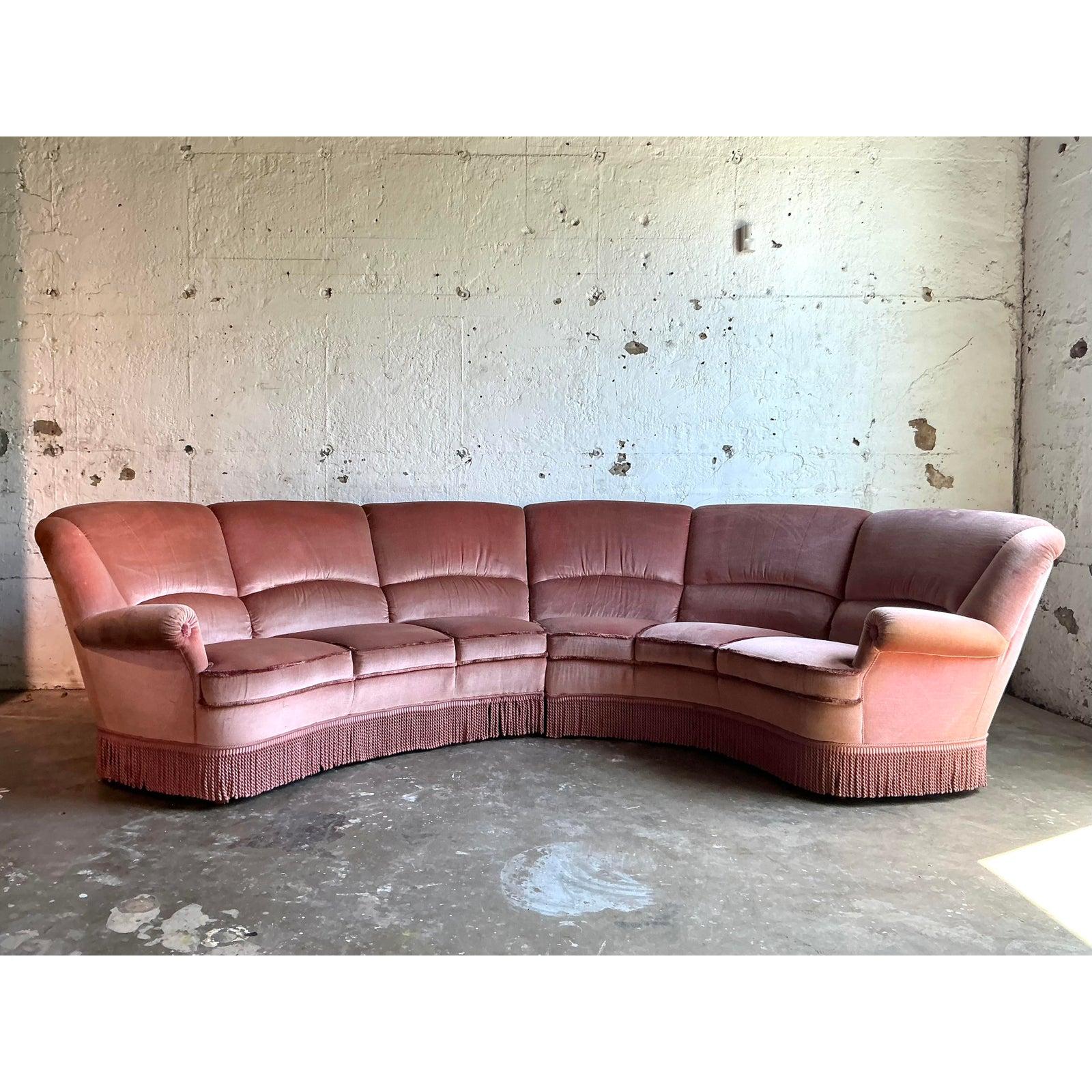 Embrace cinematic glamour with this breathtaking vintage channel-tufted sectional sofa. Defined by its magnificent, sweeping curve and upholstered in a sumptuous dusty rose velvet, this piece is the epitome of Hollywood Regency opulence. The