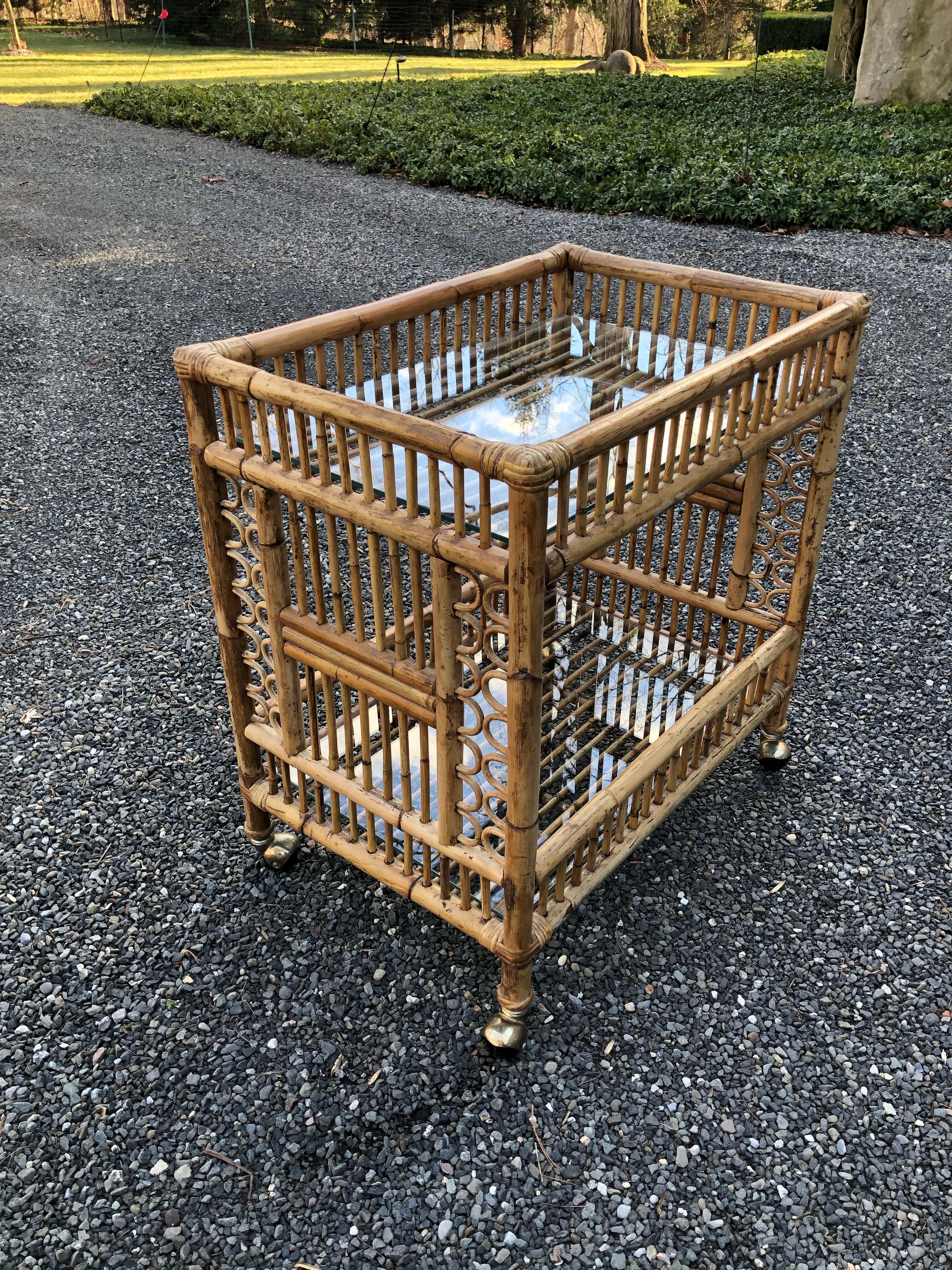 A midcentury bar cart in bamboo having two glass shelves for holding glasses, bottles and ice. The bamboo is a great color and is in excellent condition. The cart is easy to move as it is on casters.