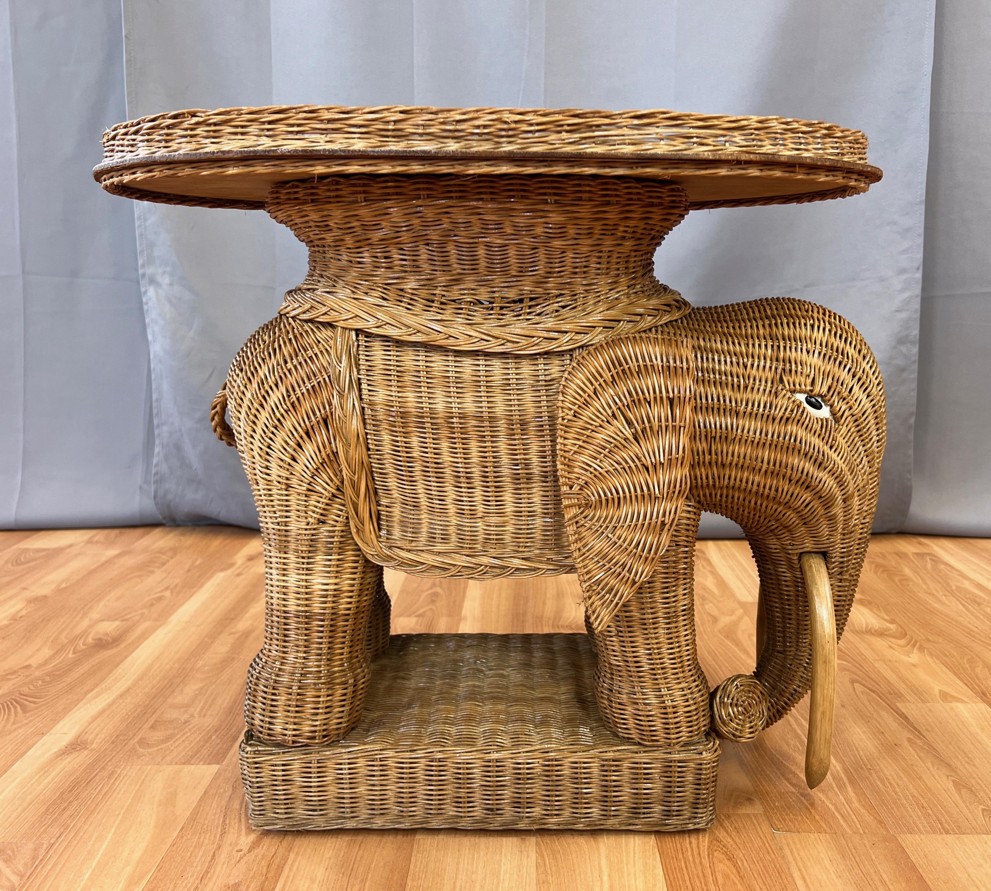 A circa 1970s natural wicker and rattan elephant side table with removable serving tray.

Finely crafted Bohemian chic at its most charming and timeless, with an artfully hand-woven natural wicker form accented by painted eyes and bent rattan tusks.