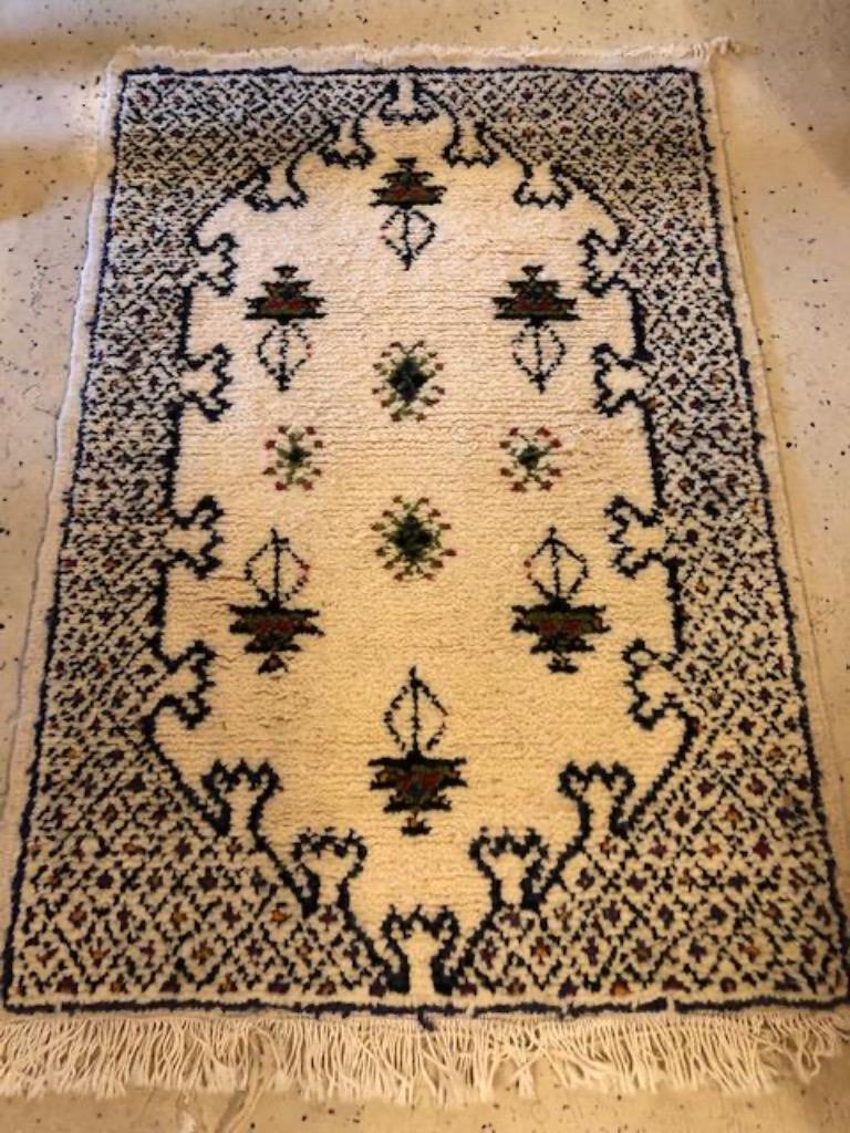 Ein schöner marokkanischer Teppich im Boho-Chic-Stammesstil mit geometrischen und Stammesmotiven auf weißem Hintergrund. Der Teppich ist aus hochwertiger Schafwolle handgewebt und bringt einen Hauch von Stil und Exotik in Ihren Raum.