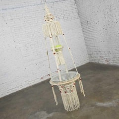 Hängetisch aus weißer Kordel mit runder Glasplatte und grüner Topf im Boho Chic-Stil