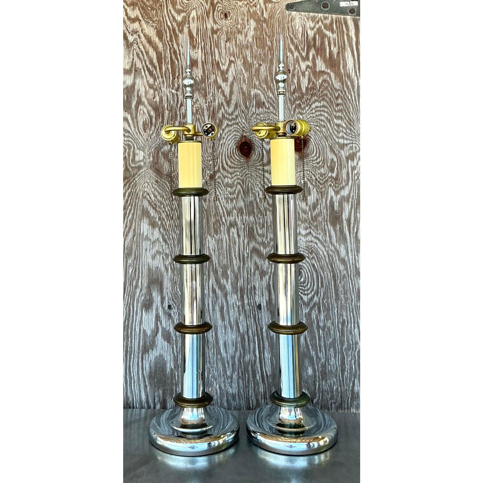 Cette superbe paire de lampes de table à pilier vintage fait sensation. Incarnant l'attrait luxueux du style Hollywood Regency et les lignes épurées du design Mid-Century Modern, ces lampes présentent un mélange captivant de chrome poli et d'accents
