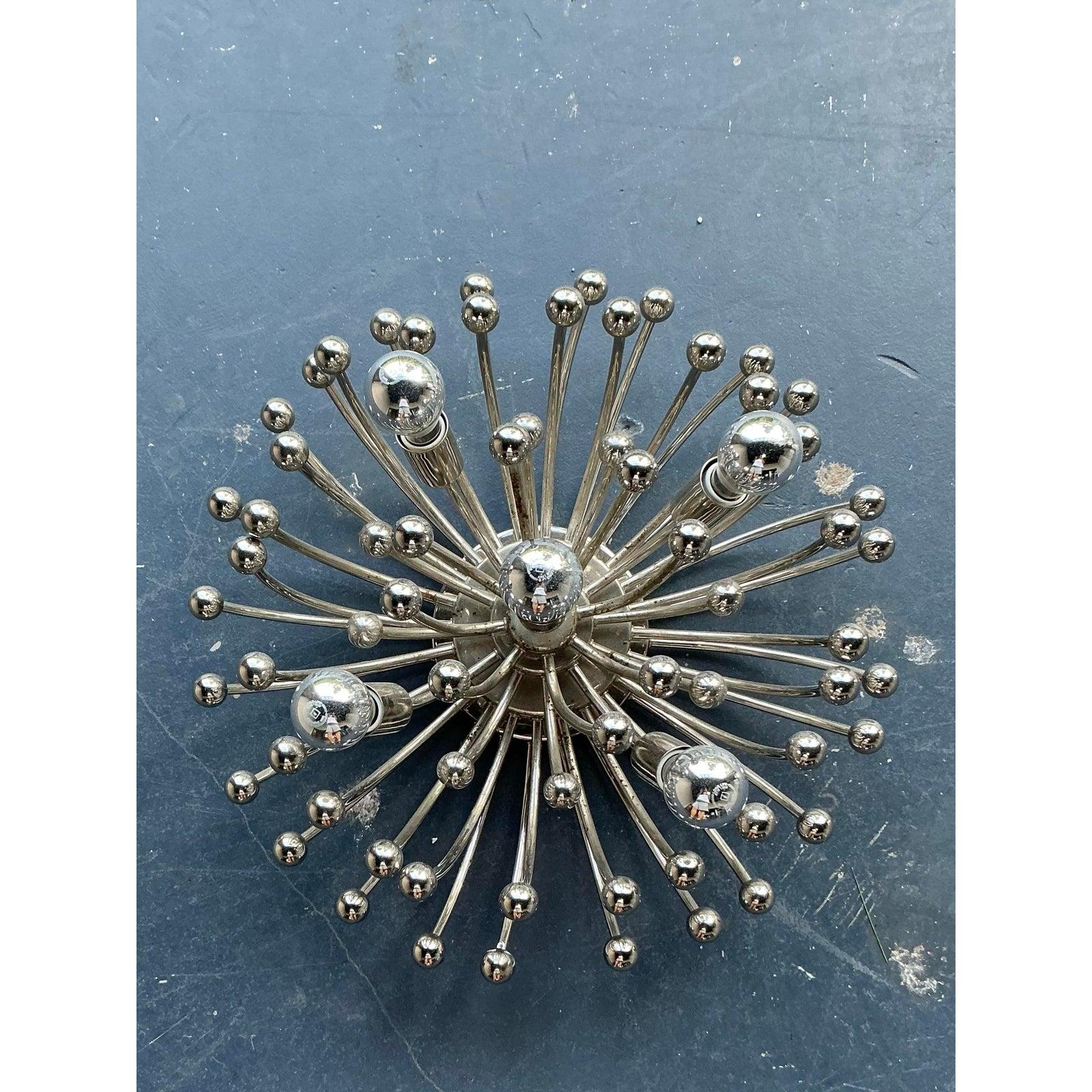 This spectacular vintage chandelier captures the excitement and sculptural dynamism of the Atomic Age and Mid-Century Modern design. Resembling a radiant bursting dandelion or a Sputnik satellite, the fixture is composed of numerous curved chrome