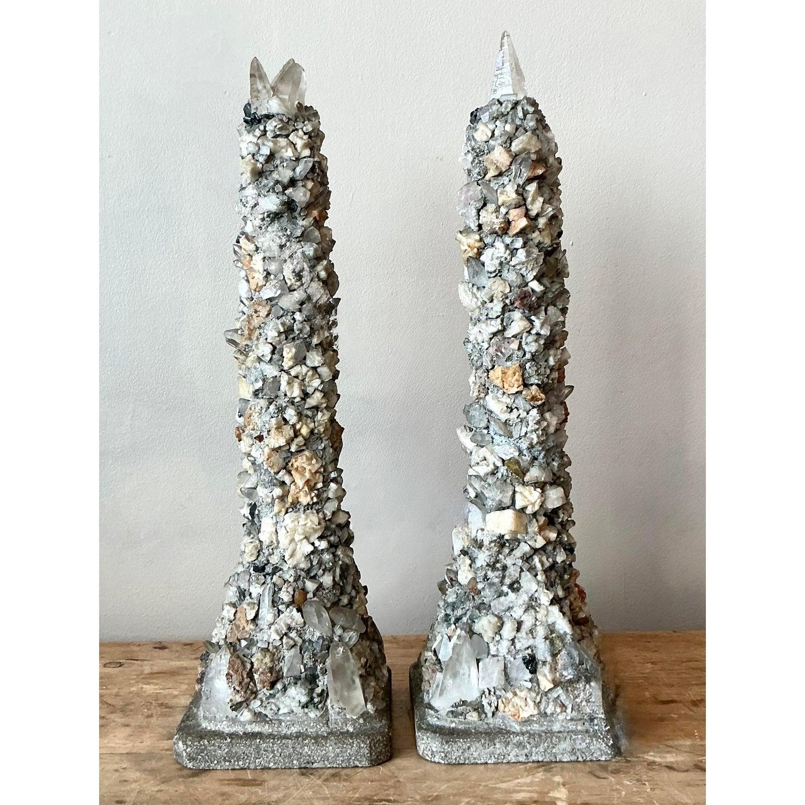 Presenta un'affascinante coppia di obelischi d'epoca, ciascuno incrostato a mano con un'accattivante serie di pietre naturali e culminante in un'impressionante punta di cristallo di quarzo chiaro. Questi pezzi decorativi unici fondono la bellezza