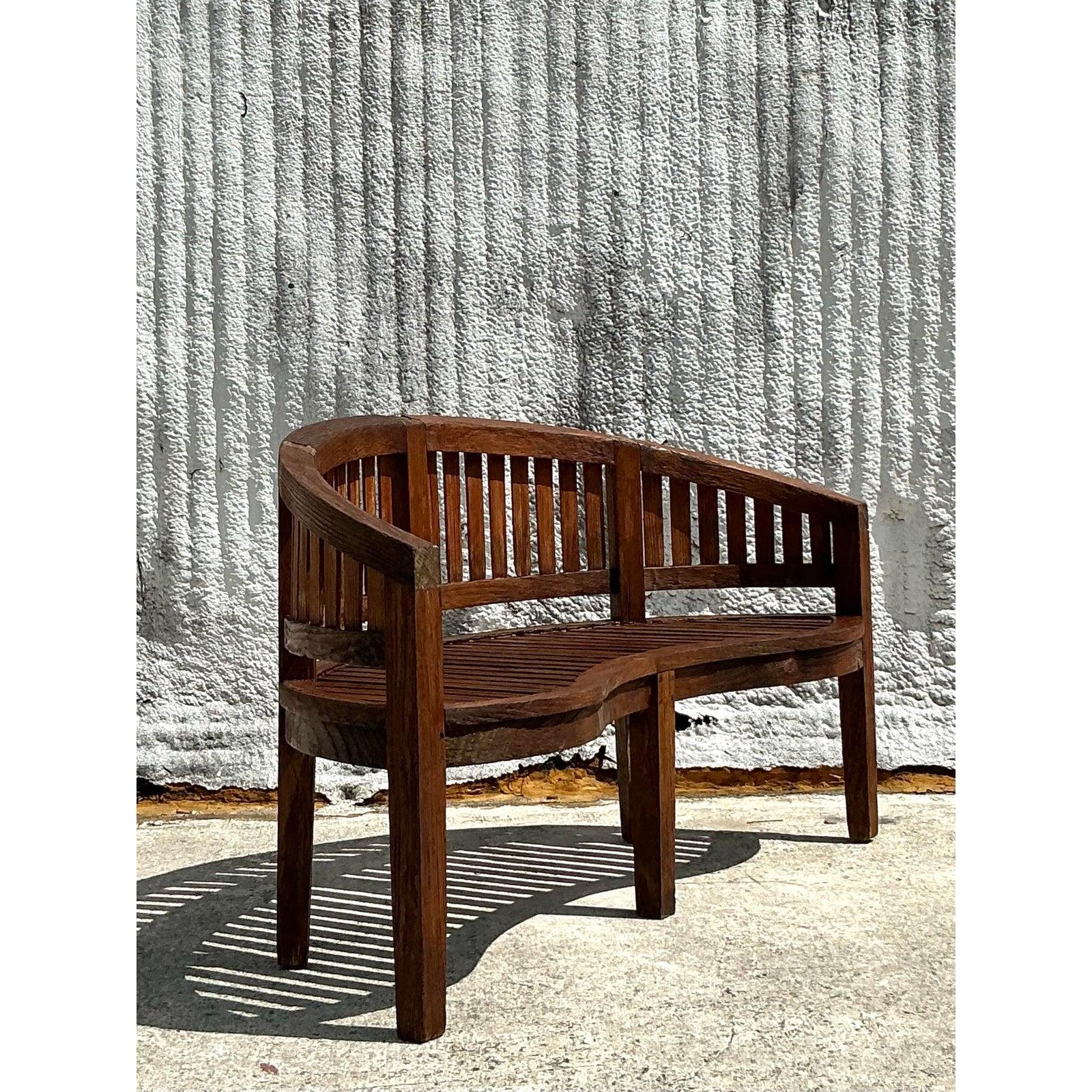 Elevate your outdoor or indoor space with this stunning vintage curved teak bench. Crafted from solid teak wood, this beautifully curved design offers both aesthetic charm and functional comfort. The slatted backrest and seat create a timeless look