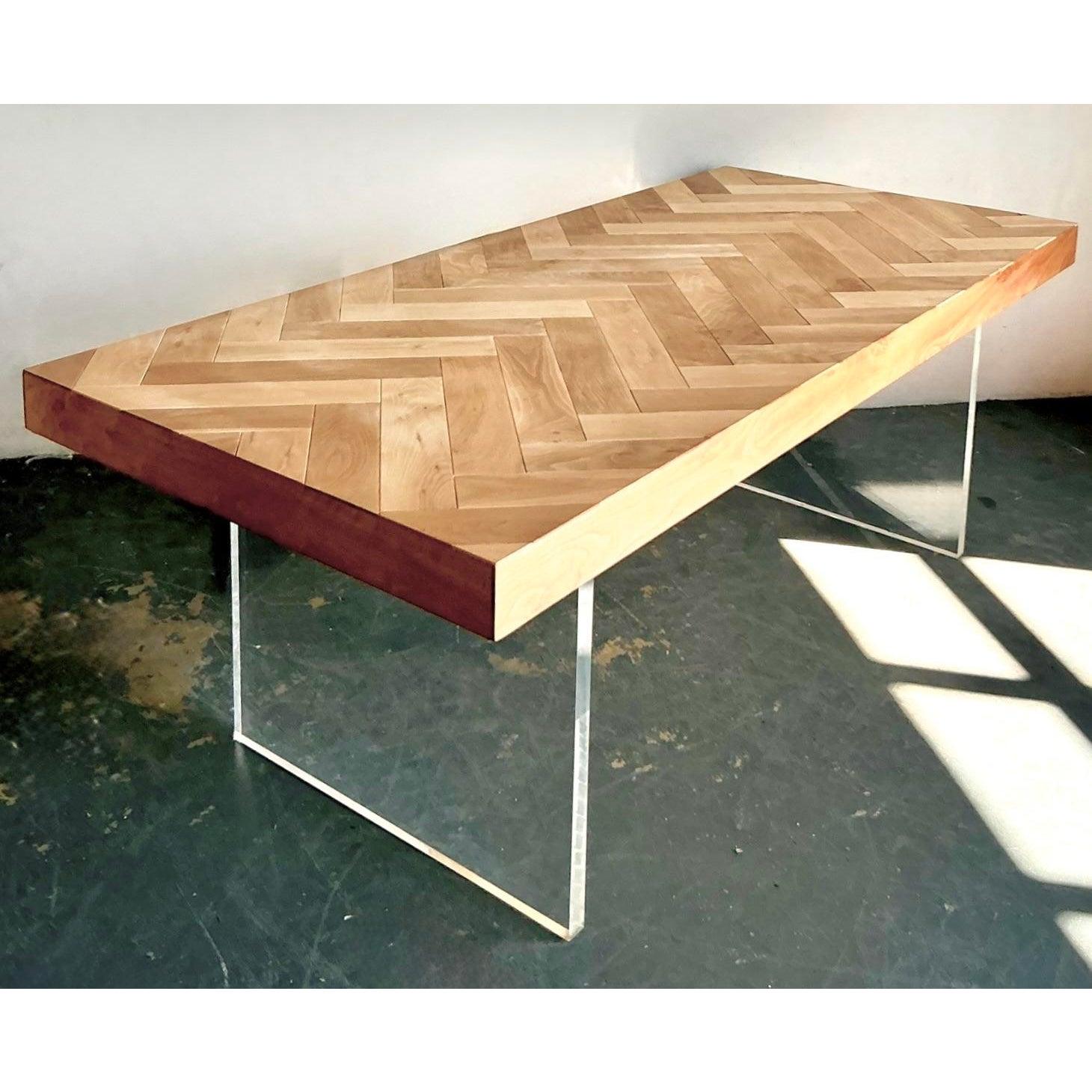 This spectacular, custom-designed dining table epitomizes sophisticated contemporary craftsmanship, expertly blending organic texture with transparent modernity. The substantial tabletop features an exquisite chevron parquet pattern composed of