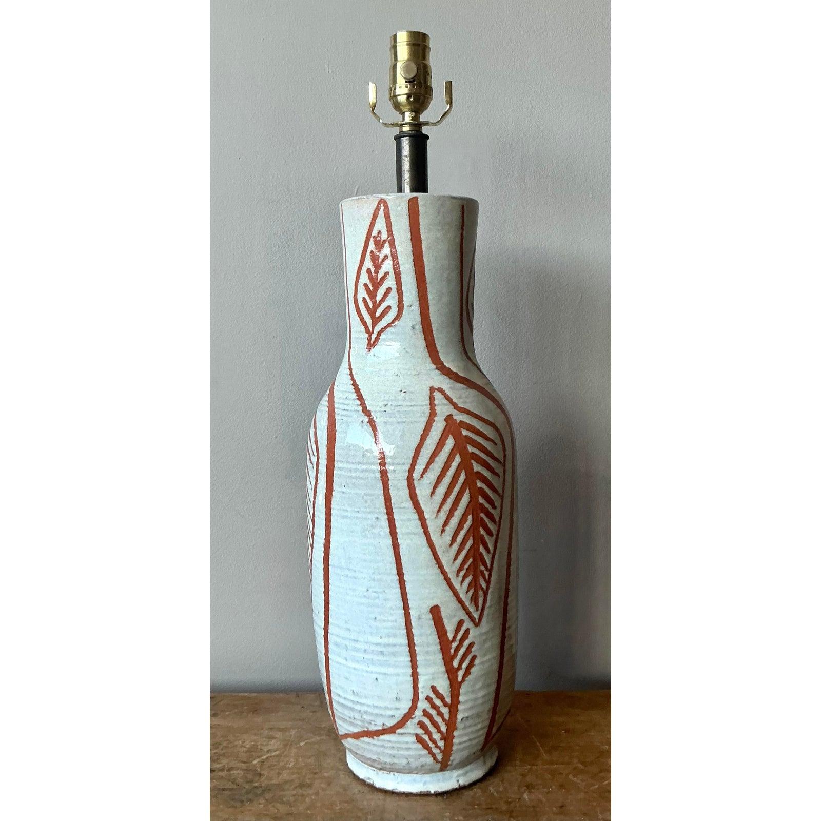 Cette lampe de table vintage unique est un exemple frappant de la céramique de studio du milieu du siècle, célébrant la forme organique et le design abstrait. La base en céramique présente une silhouette en sablier avec une glaçure épaisse et