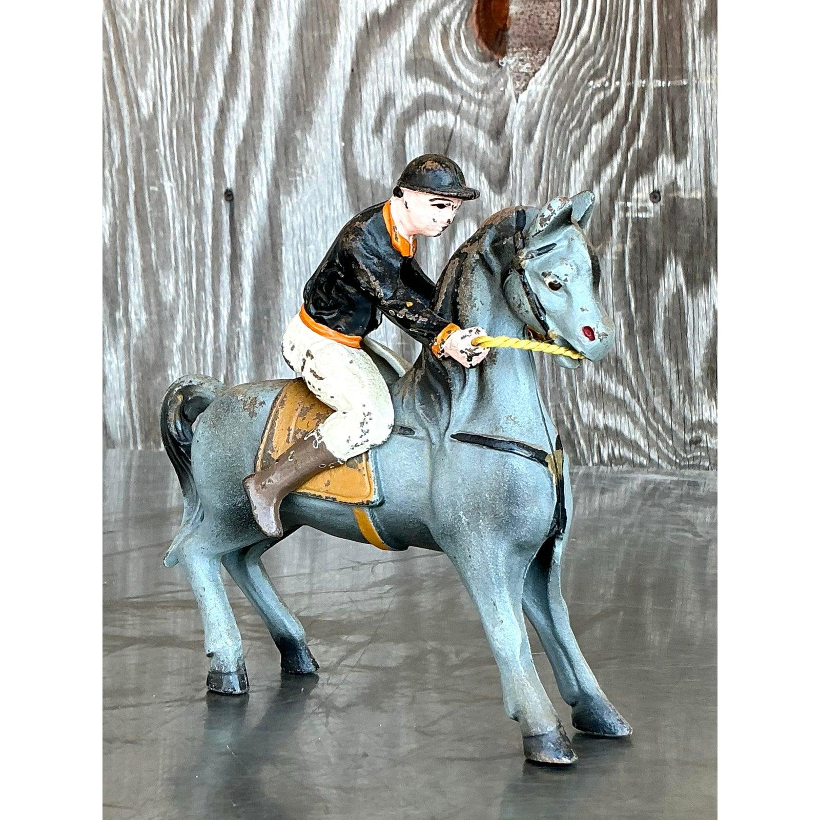 Cattura lo spirito di avventura e il fascino classico dell'equitazione con questo cavaliere a cavallo vintage Boho diecast. Realizzata in resistente ferro battuto e dipinta a mano in delicate tonalità di grigio-blu, avorio e ocra, questa scultura di