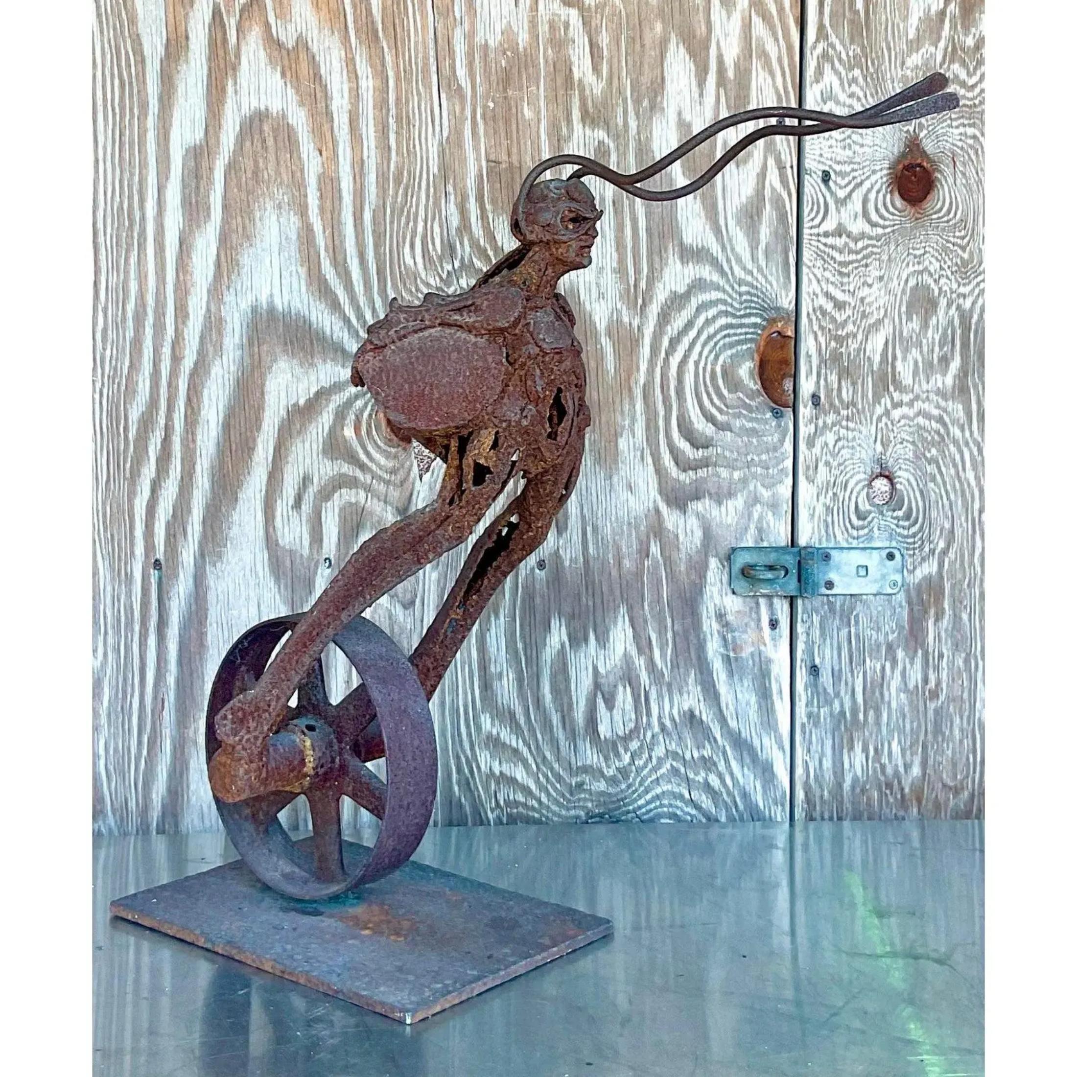 Vintage Boho distressed sculpture. An intriguing composition of a figure in a helmet riding on a wheel. So awesome. Acquired from a Palm Beach estate.