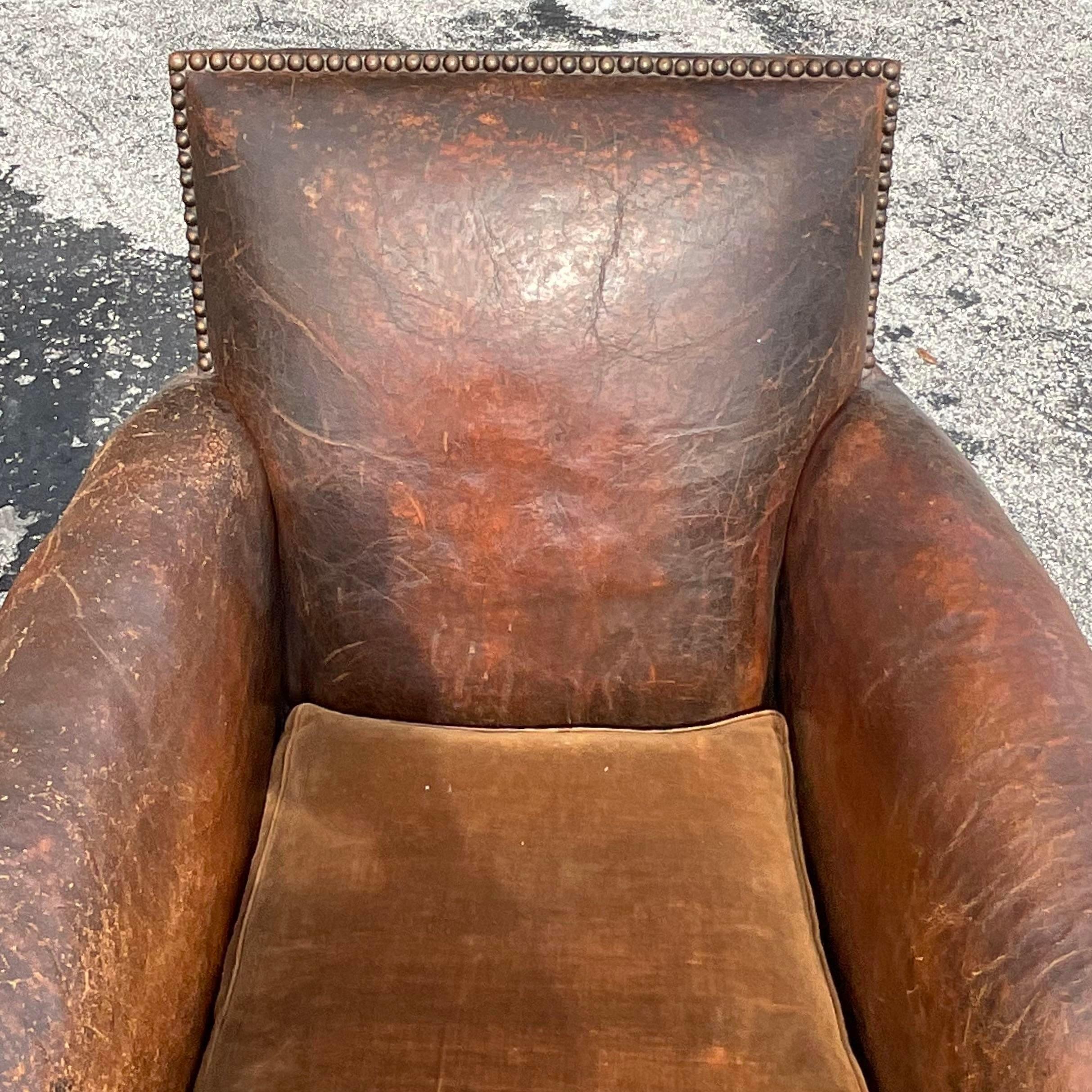 An incredible pair of vintage Boho club chairs. Chic 1920s French Art Deco in a distressed leather upholstery. A caramel colored mohair cushion. A nailhead trim adds to the charm. Acquired from a Palm Beach estate. 