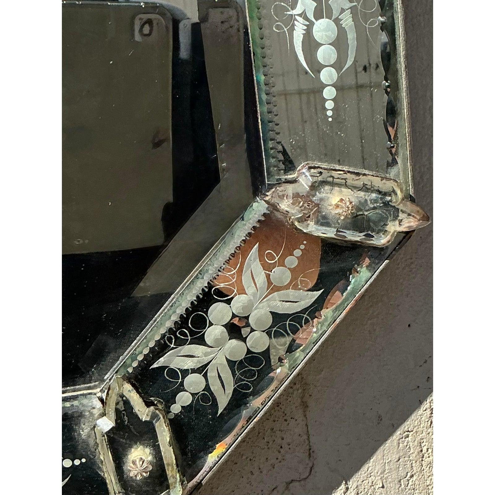 D'une élégance intemporelle, ce miroir vintage en verre vénitien est un mélange étonnant d'artisanat complexe et de charme bohème. Les motifs floraux gravés à la main, délicatement encadrés dans des panneaux miroirs biseautés, présentent une