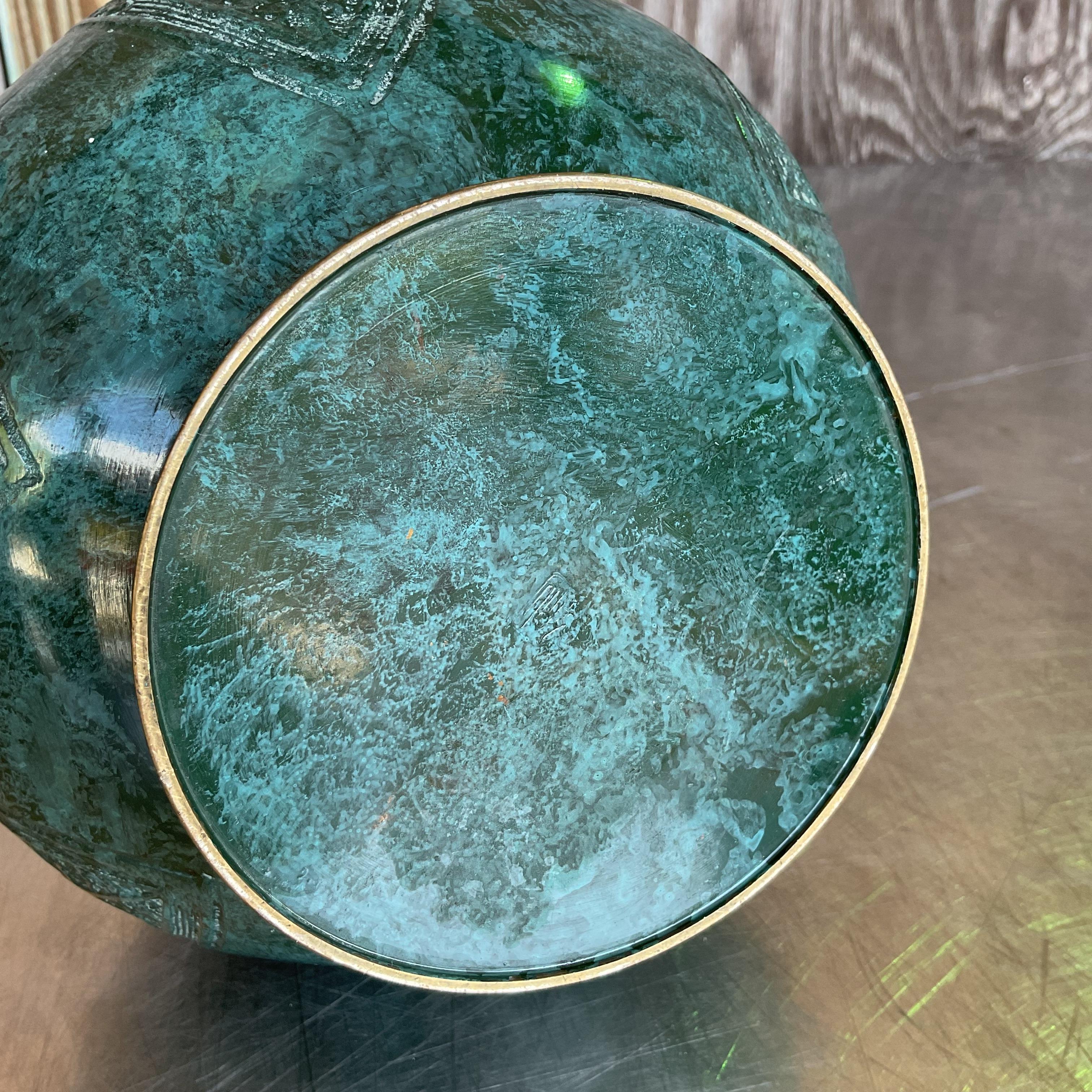 Vintage Boho Double Elephant Patinated Metal Vase, featuring two intricately detailed elephants and a rich, weathered finish. A distinctive piece that adds bohemian charm and character to your decor. Acquired from a Palm Beach estate.