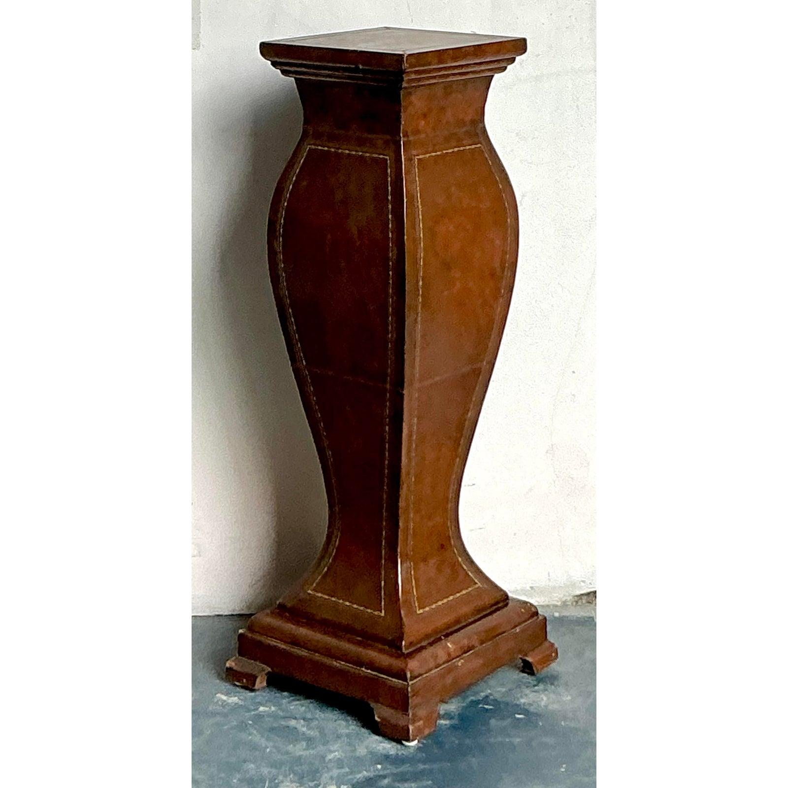This elegant pedestal showcases exceptional craftsmanship, utilizing a tailored leather wrap to reinterpret a classical architectural form. The stand features a striking hourglass silhouette, grounded by a tiered, fluted base and topped with a flat,