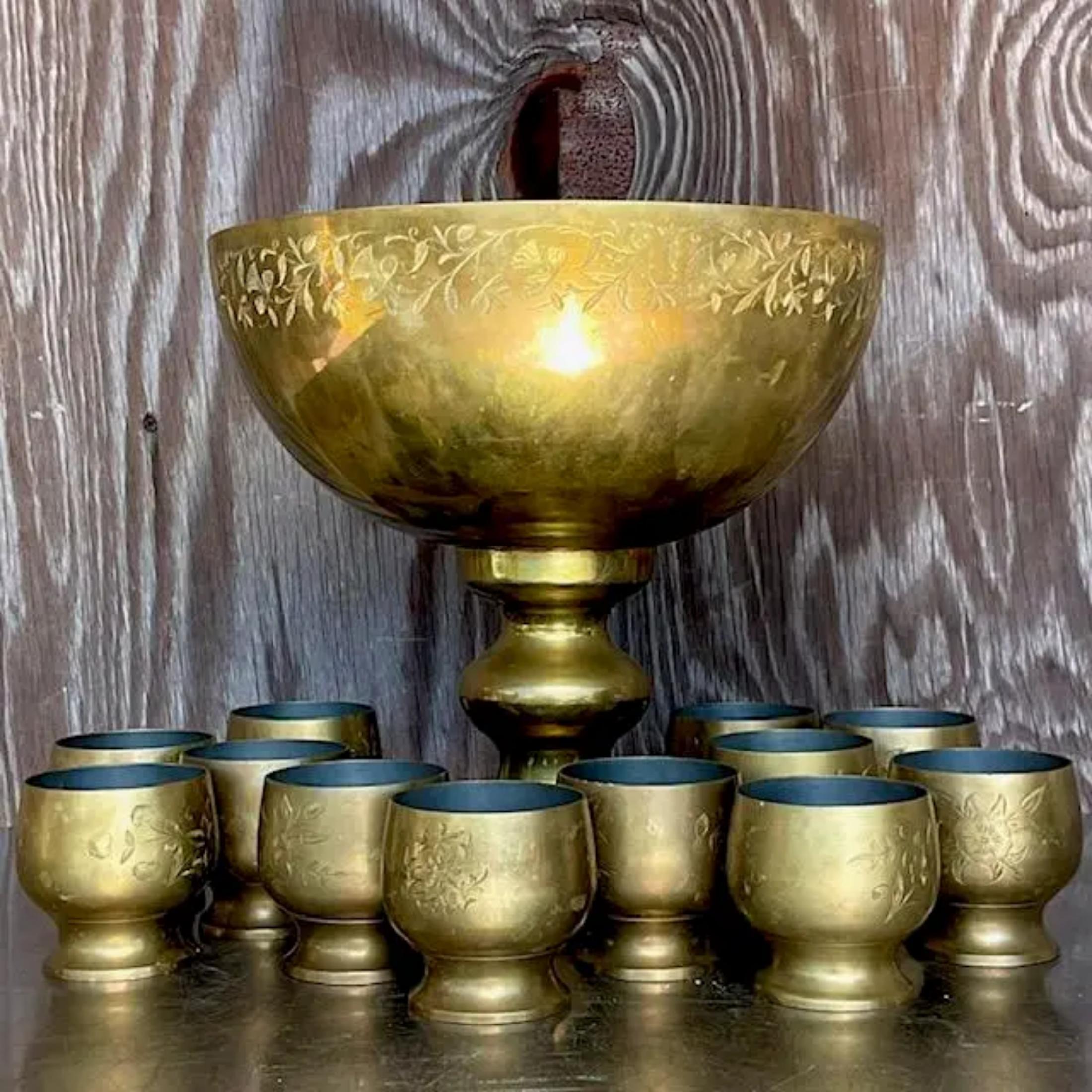 A stunning vintage Boho punch bowl set. A gorgeous etched brass finish with a tin interior. 12 individual serving cups. The bowl would also be gorgeous on a center table filled with orchids. Acquired from a Palm Beach estate.