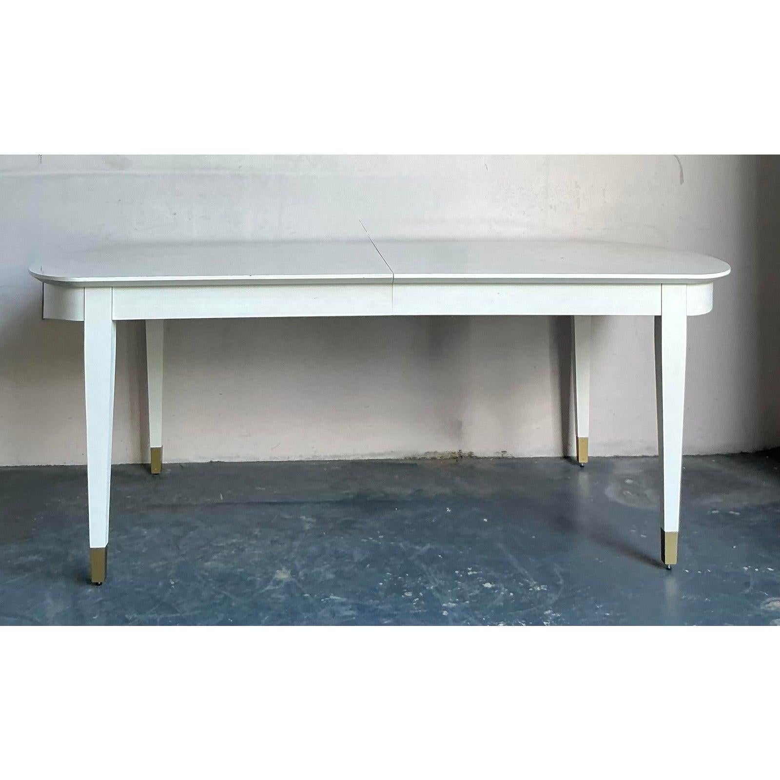 Questo eccezionale tavolo da pranzo di stile Mid-Century Modern fonde linee pulite di ispirazione danese con eleganti dettagli Hollywood Regency, offrendo una scala monumentale per intrattenimenti sofisticati. Il tavolo presenta un elegante piano a