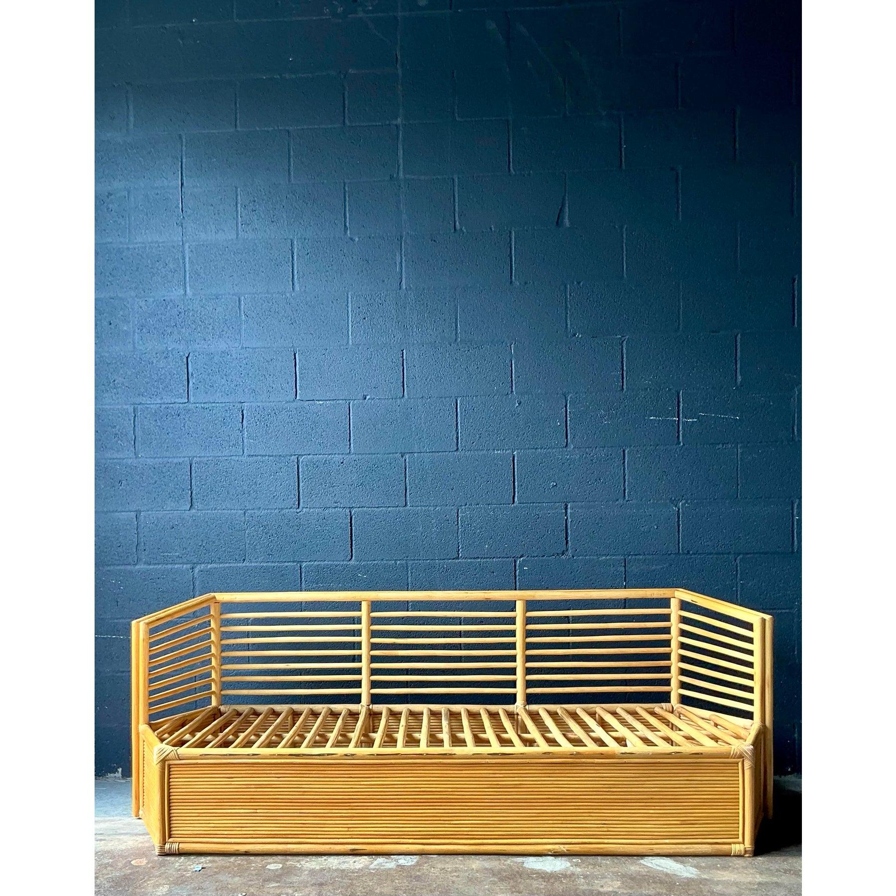 Ce cadre de canapé vintage expansif incarne la sophistication naturelle du design tropical du milieu du siècle, offrant une base polyvalente pour les intérieurs bohémiens ou côtiers. Entièrement fabriquée en rotin couleur miel et en roseaux liés,