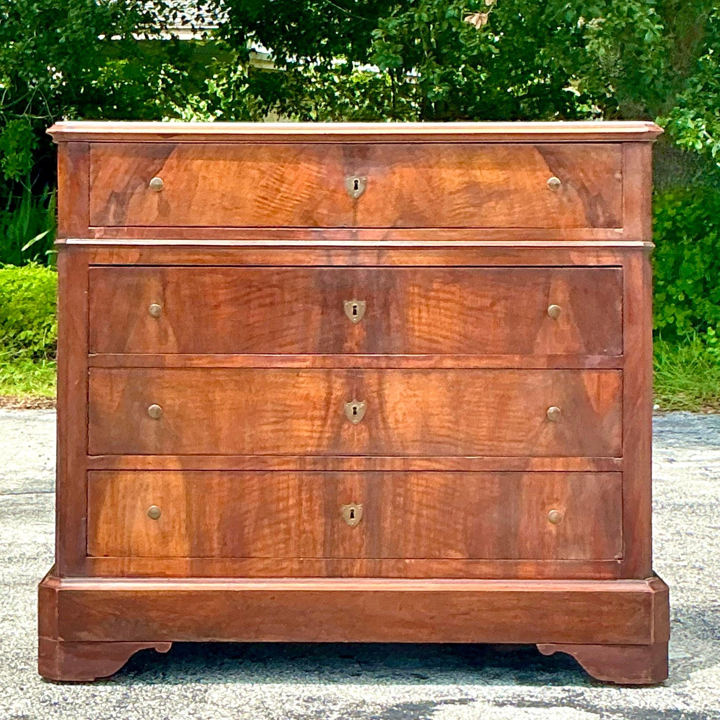 This Vintage Boho Flame Mahogany Marble Top Chest of Drawers is a stunning blend of elegance and warmth. The rich flame mahogany wood contrasts beautifully with the luxurious marble top, offering both style and storage with a bohemian twist. A