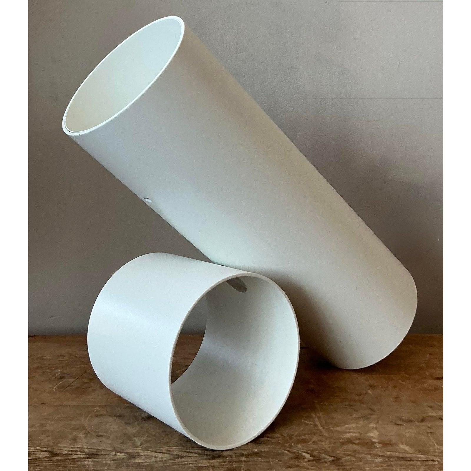 Esta lámpara de sobremesa excepcionalmente minimalista encarna a la perfección la pureza de formas central en las filosofías de diseño moderno y posmoderno de mediados de siglo. Construida a partir de un tubo cilíndrico sencillo y limpio