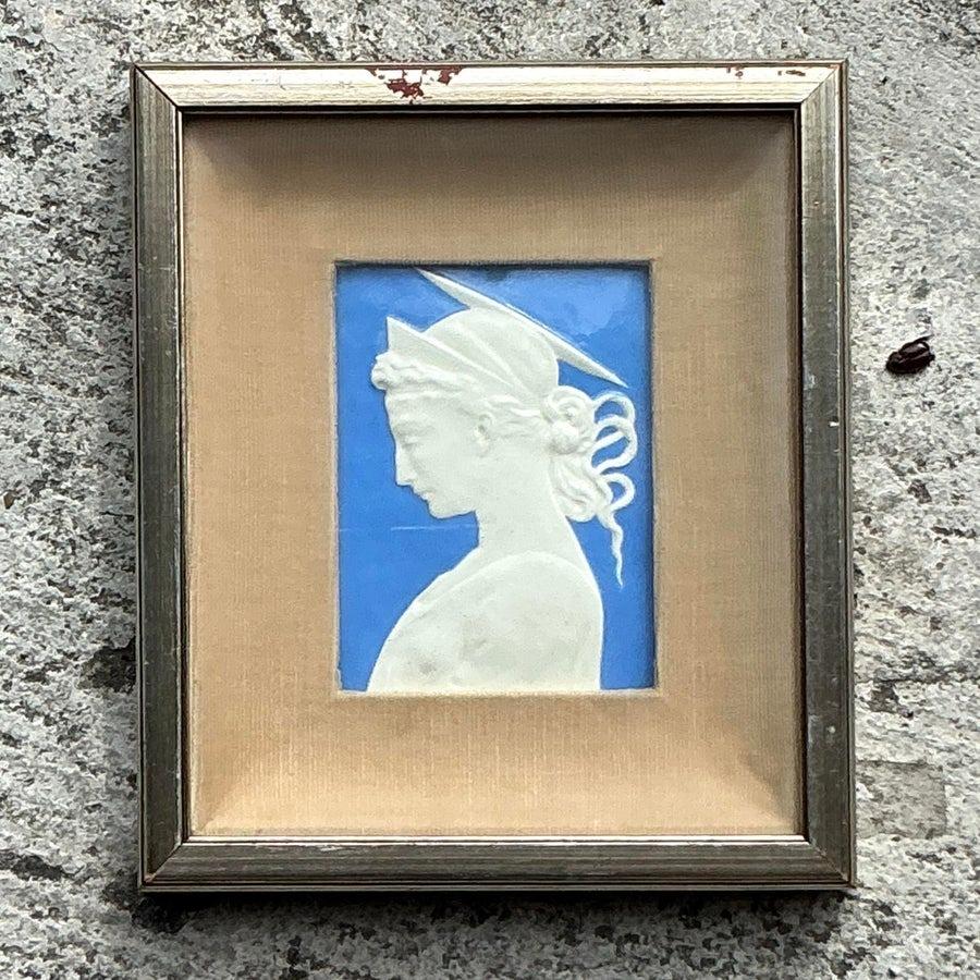 Fangen Sie die Essenz zeitloser Eleganz mit diesem gerahmten Keramikrelief im Vintage-Boho-Stil ein. Das zarte weiße Profil vor einem auffälligen blauen Hintergrund wird von einem einfachen, aber raffinierten Rahmen umschlossen, der einen dezenten