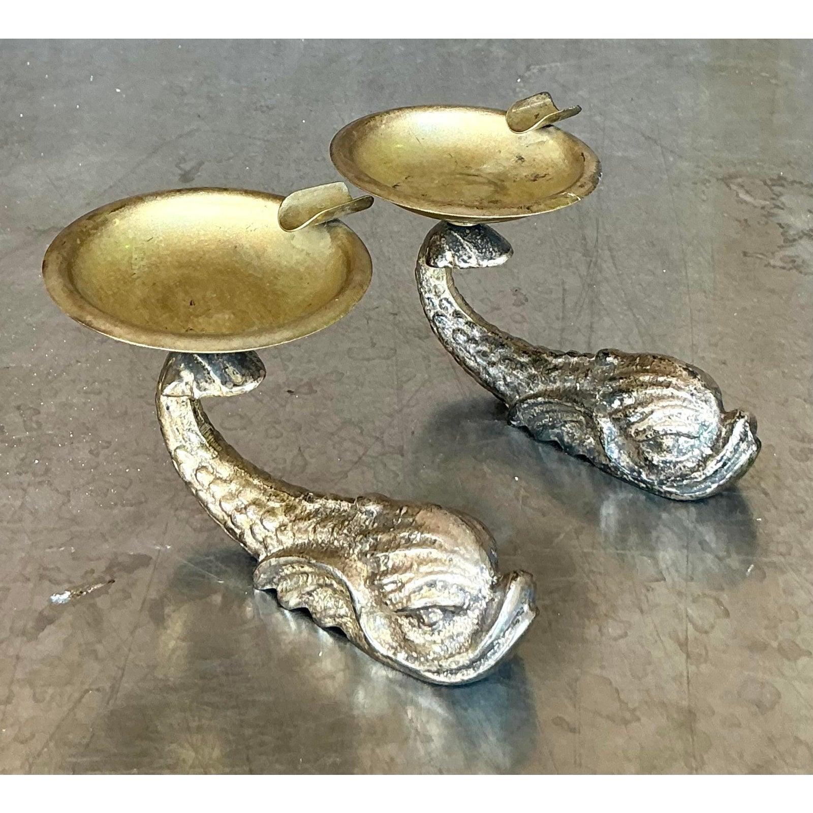 A touch of whimsical glamour, this delightful pair of vintage dolphin ashtrays channels the playful spirit of Hollywood Regency design. Each piece features a beautifully detailed, silvered dolphin base, its tail elegantly sweeping upward to support