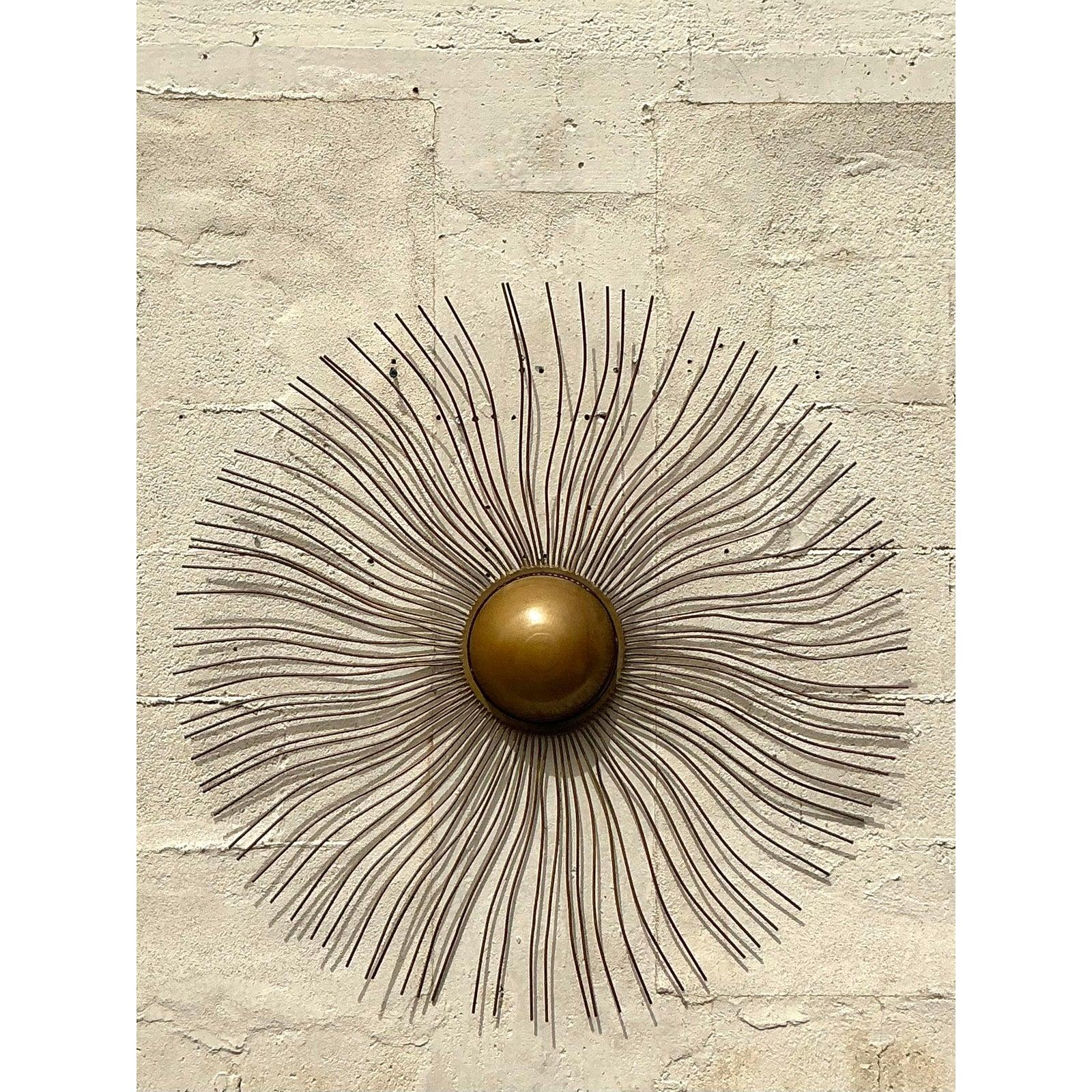 Fai una dichiarazione audace con questa splendida scultura da parete boho sunburst vintage. Caratterizzato da un intricato design radiante con eleganti raggi in metallo dorato, questo pezzo cattura la bellezza dell'estetica moderna e bohémien di
