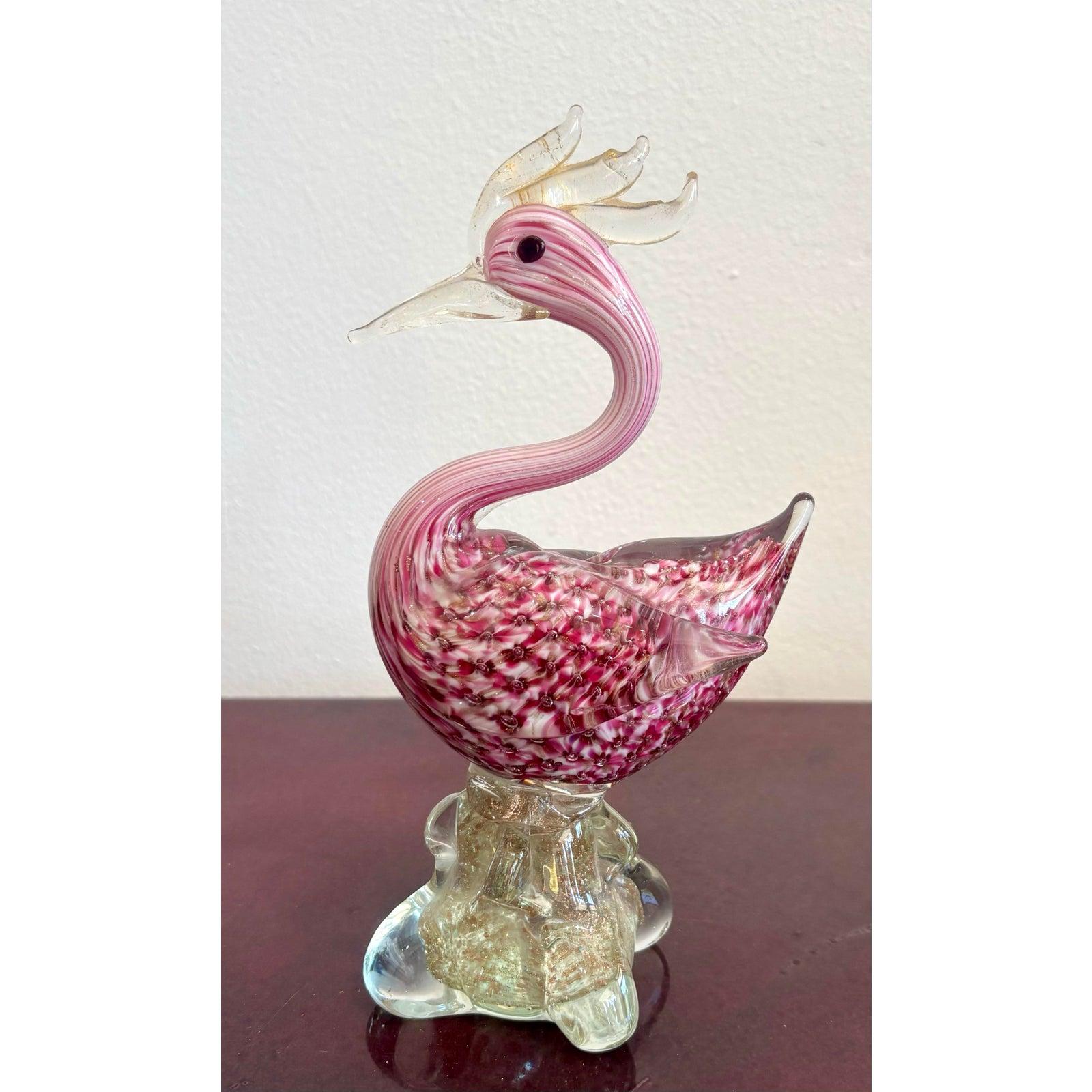 Questa stravagante scultura di uccelli in vetro è una celebrazione del fascino e dell'artigianato. Con il suo piumaggio rosa, la cresta a forma di corona e l'elegante collo arcuato, ha il fascino di una creatura mitica a metà strada. Il corpo è un